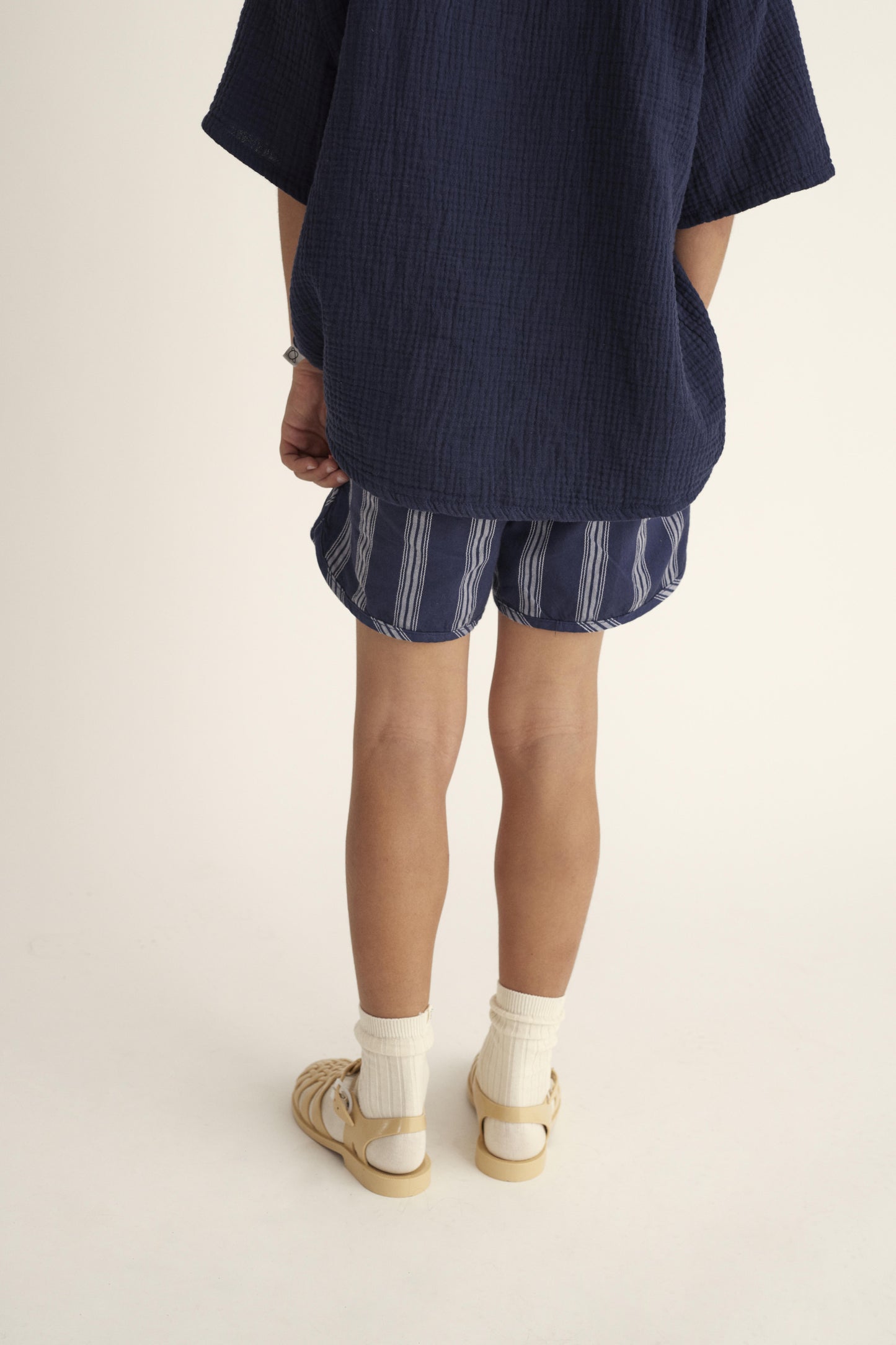 Kind trägt nachhaltige gestreifte Shorts von Cozmo aus weichem, biologischem Stoff.