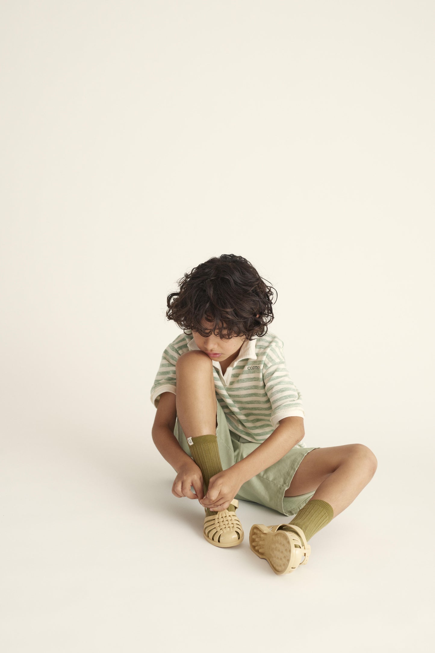 Cozmo Bermuda Shorts – Kind spielt draussen in bequemen, grünen Shorts aus biologischem Material.