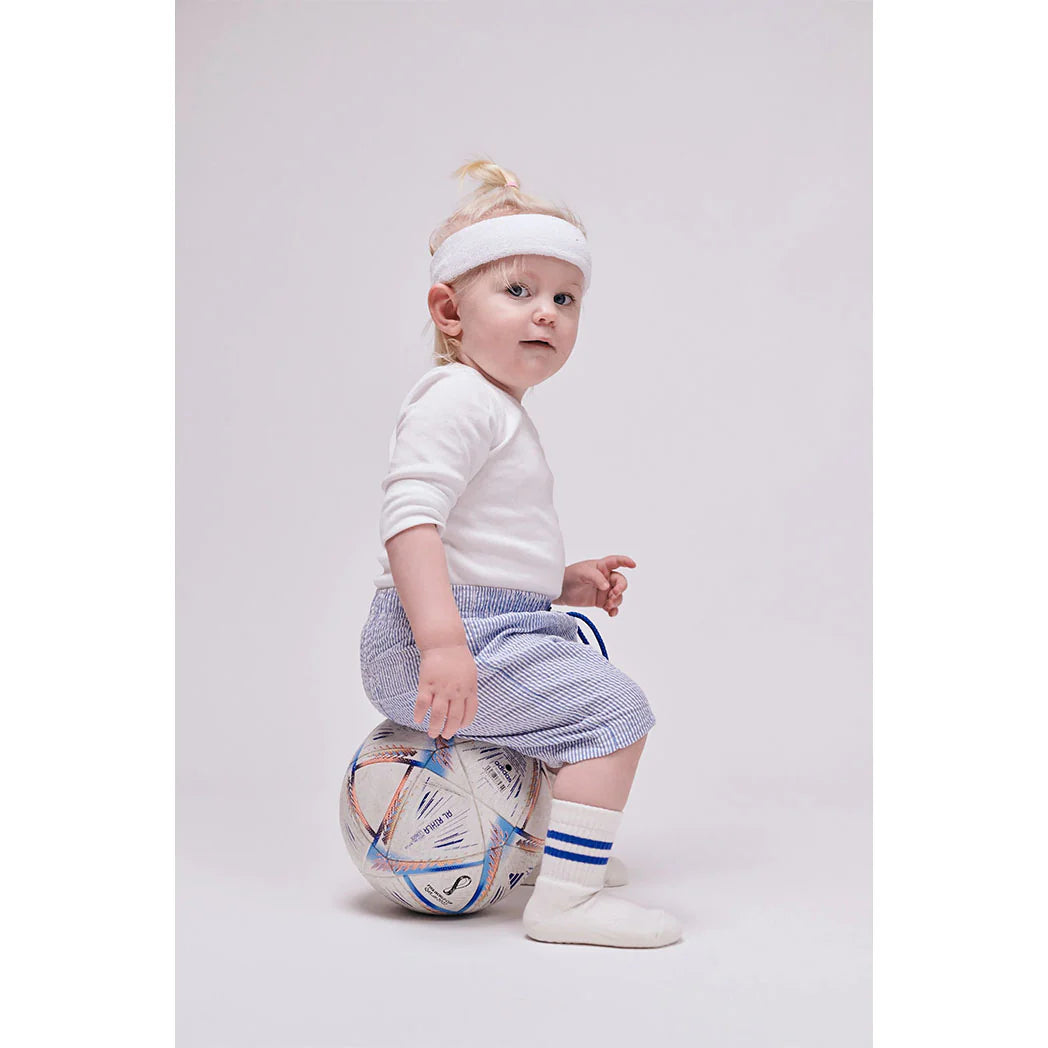 Baby trägt GoBabyGo Anti-Rutsch Socken creme mit blauen Streifen beim Spielen – Bärechind Winterthur, Zürich, Schweiz.