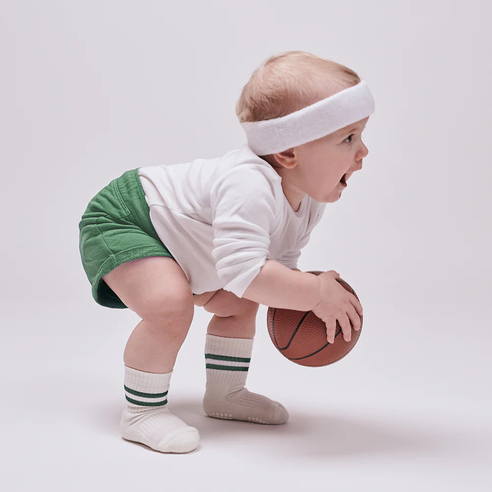 Baby trägt GoBabyGo Anti-Rutsch Socken creme mit grünen Streifen beim Spielen – Bärechind Winterthur, Zürich, Schweiz.
