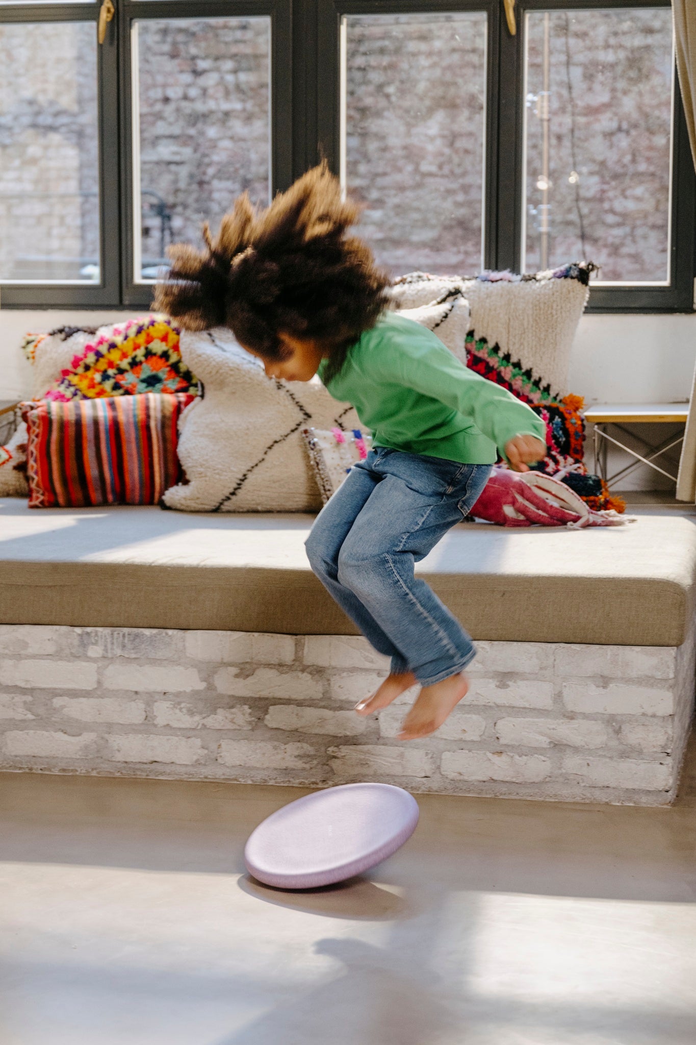 Kind springt spielerisch zum helllila Balance Board – lebendige Bewegungsszene bei Bärechind