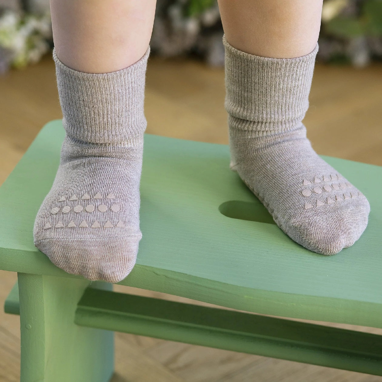 Baby in Bewegung mit sandfarbenen Anti-Rutsch-Socken von GoBabyGo – ideal für erste Schritte