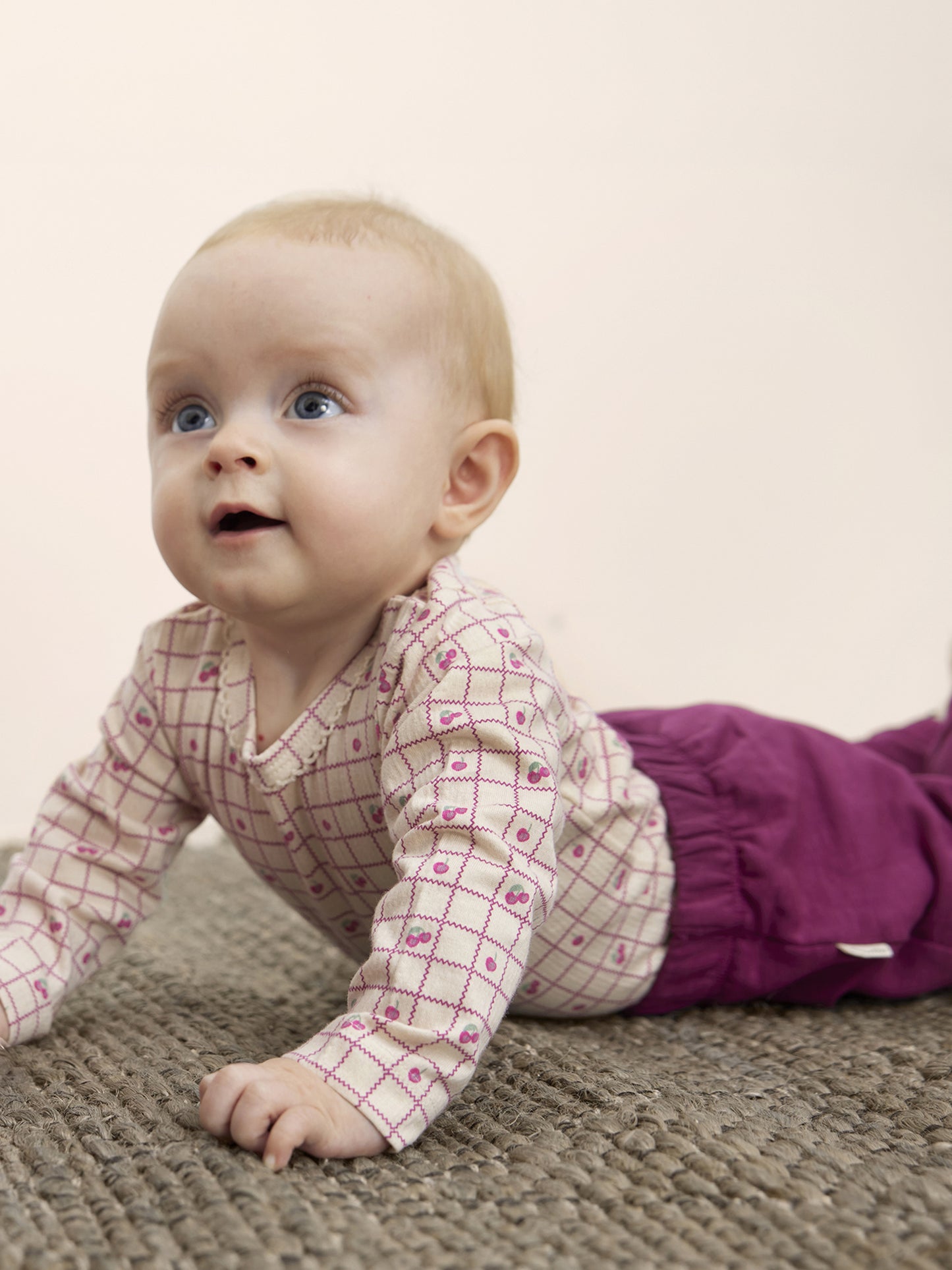 Baby trägt die bequeme Minymo Bio-Sweatpants in Himbeer – weich und flexibel