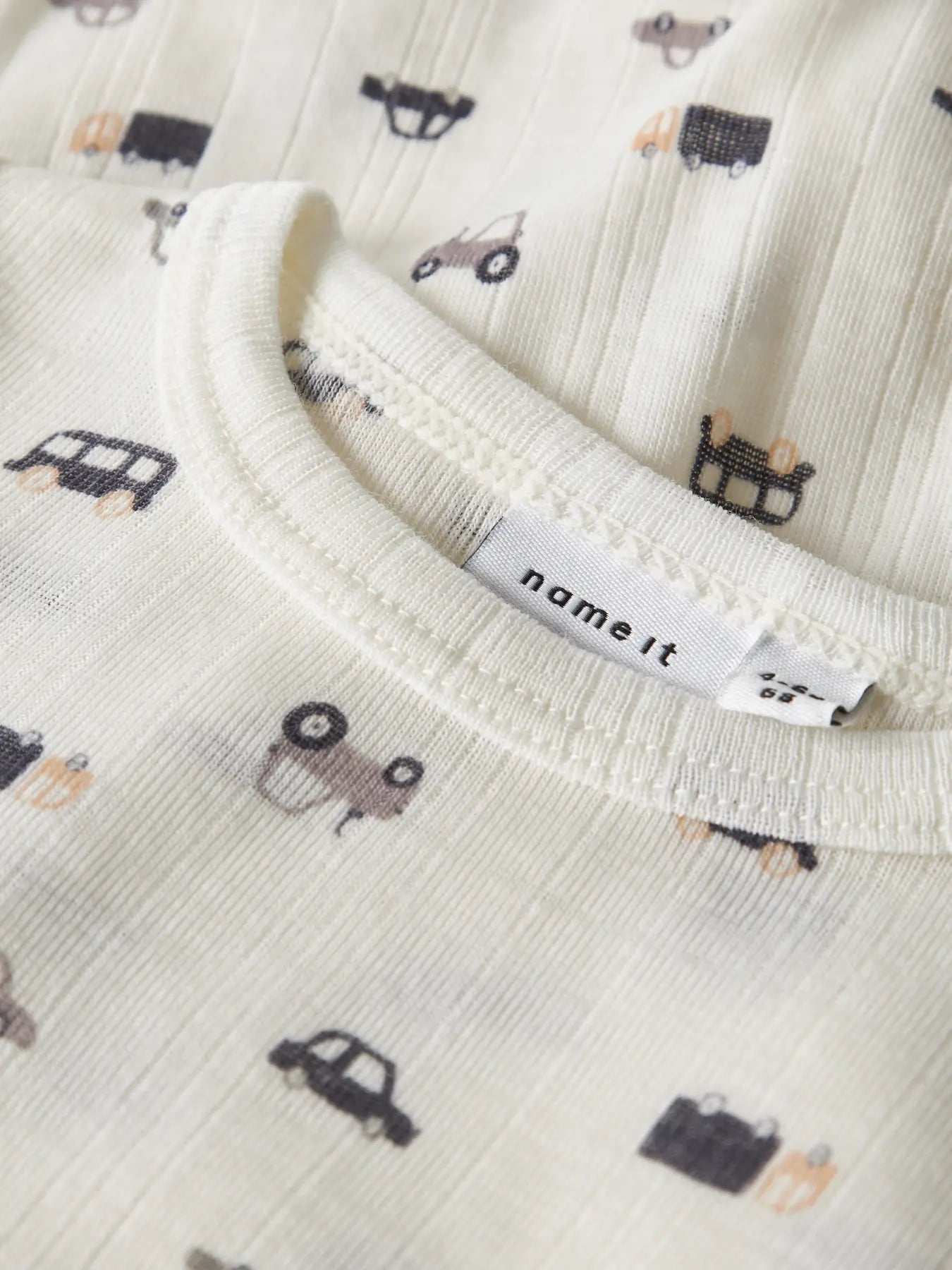 Detailaufnahme vom Babybody mit Auto-Muster aus Merinowolle in Naturweiss.