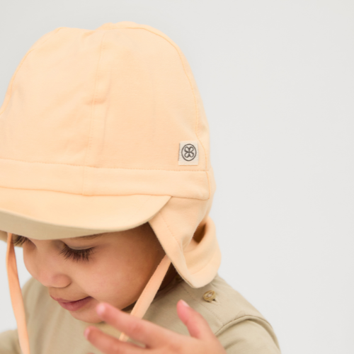 Baby trägt Cloby UV-Sonnenhut in Peachy – Weicher, atmungsaktiver Sonnenhut mit UPF 50+ Schutz für empfindliche Babyhaut. Perfekt für sonnige Tage. Jetzt in Winterthur, Zürich, Schweiz erhältlich.