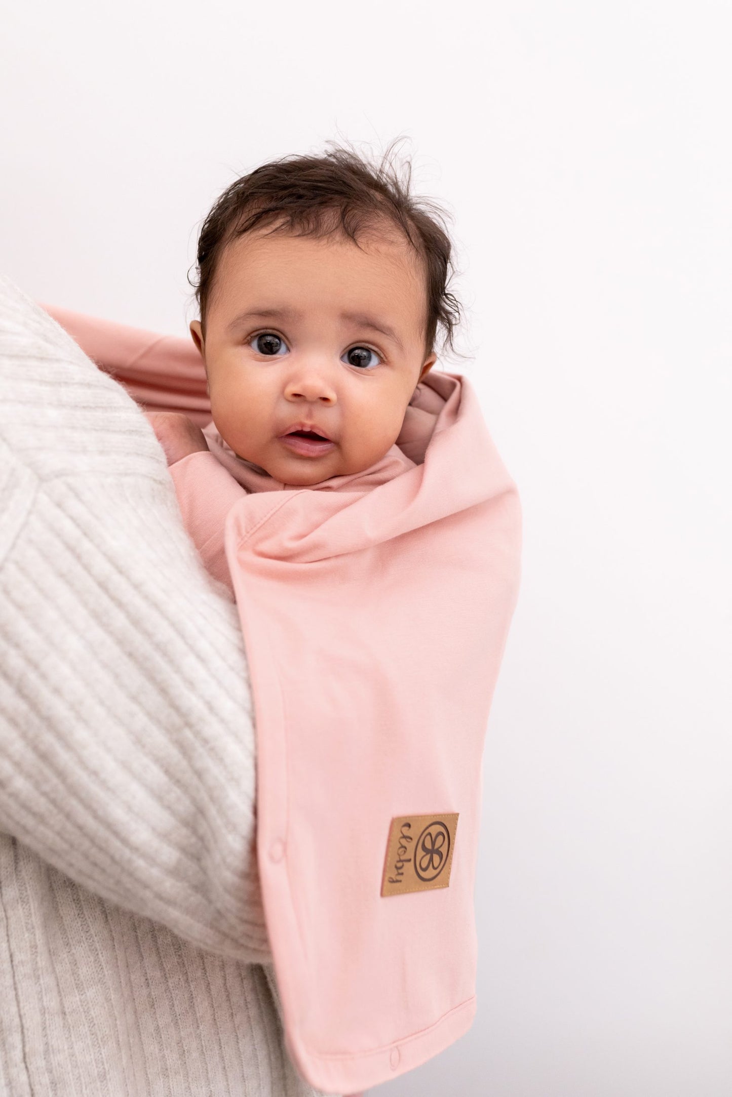 Baby mit Cloby UV Tuch Misty Rose als Sonnenschutz in der Trage im nachhaltigen Kinderladen Bärechind Winterthur Schweiz.