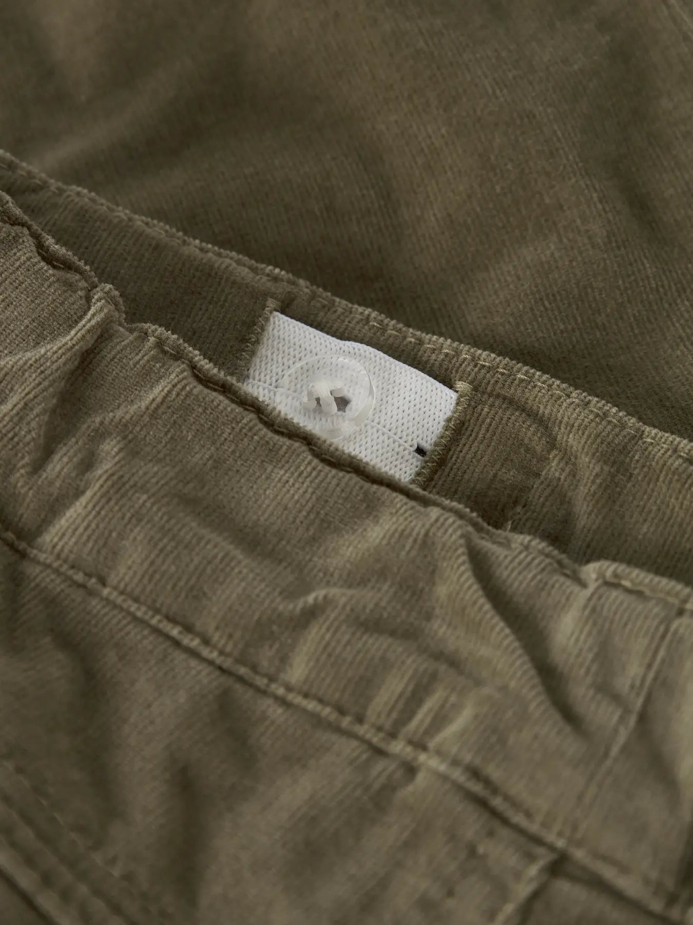 Detailaufnahme des verstellbaren Bunds einer beige Cordhose mit Baumwollfutter, erhältlich bei Bärechind in Winterthur, Zürich Schweiz.