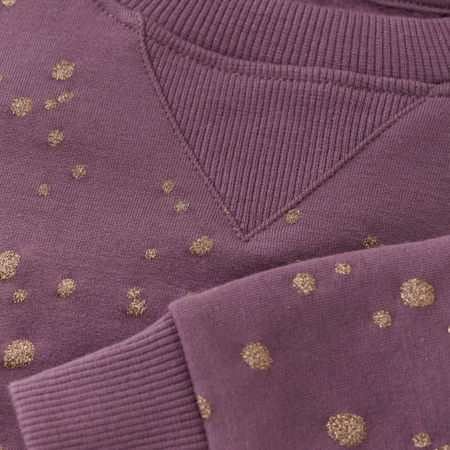 Detailaufnahme der goldenen Glitzerpunkte auf dem Creamie Sweatshirt in Lila. Ein elegantes Kinderoberteil in Winterthur, Zürich, Schweiz.
