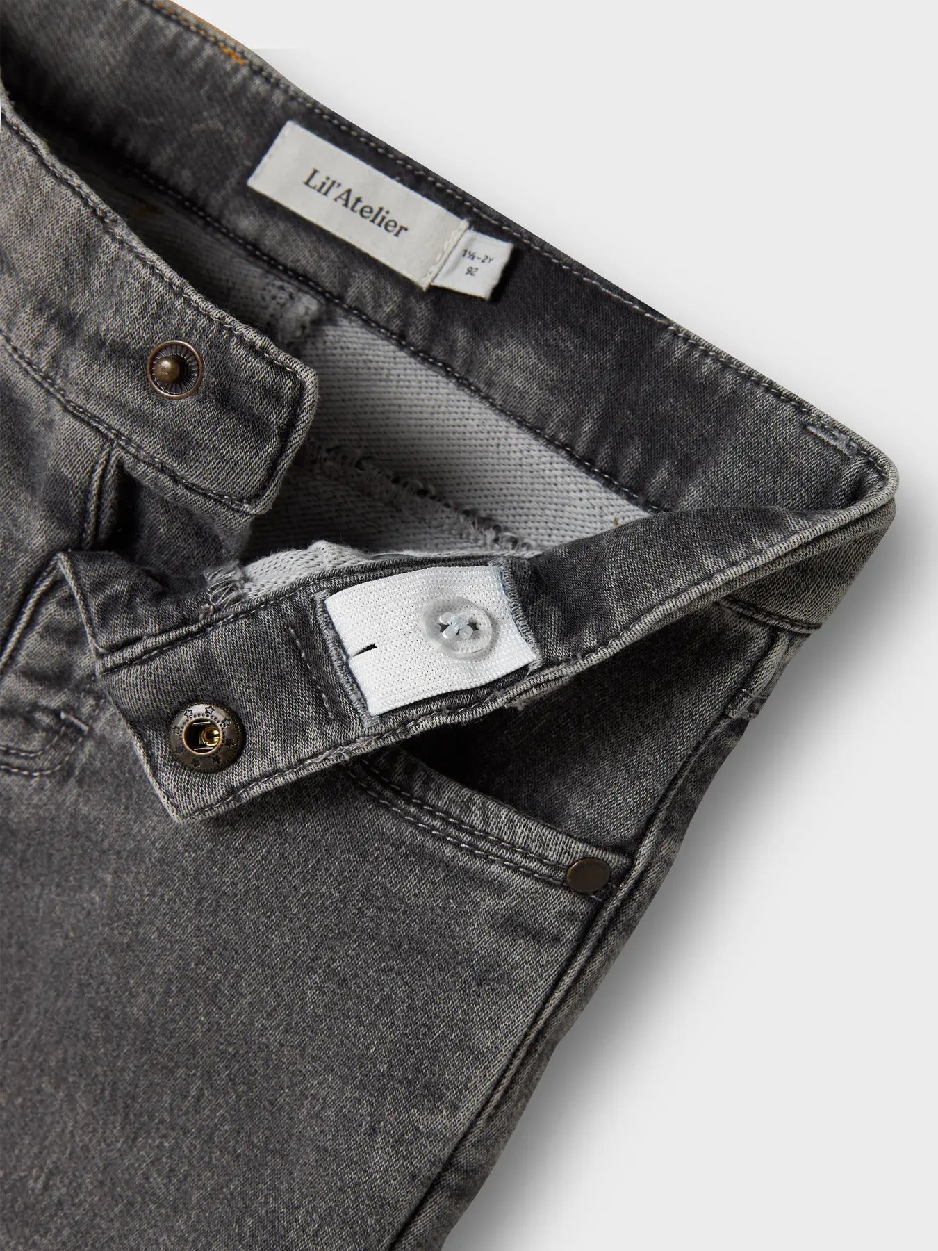 Detailaufnahme Bund mit Knopf und Gummizug der LIL'ATELIER Jeans bei Bärechind Winterthur, Zürich Schweiz.
