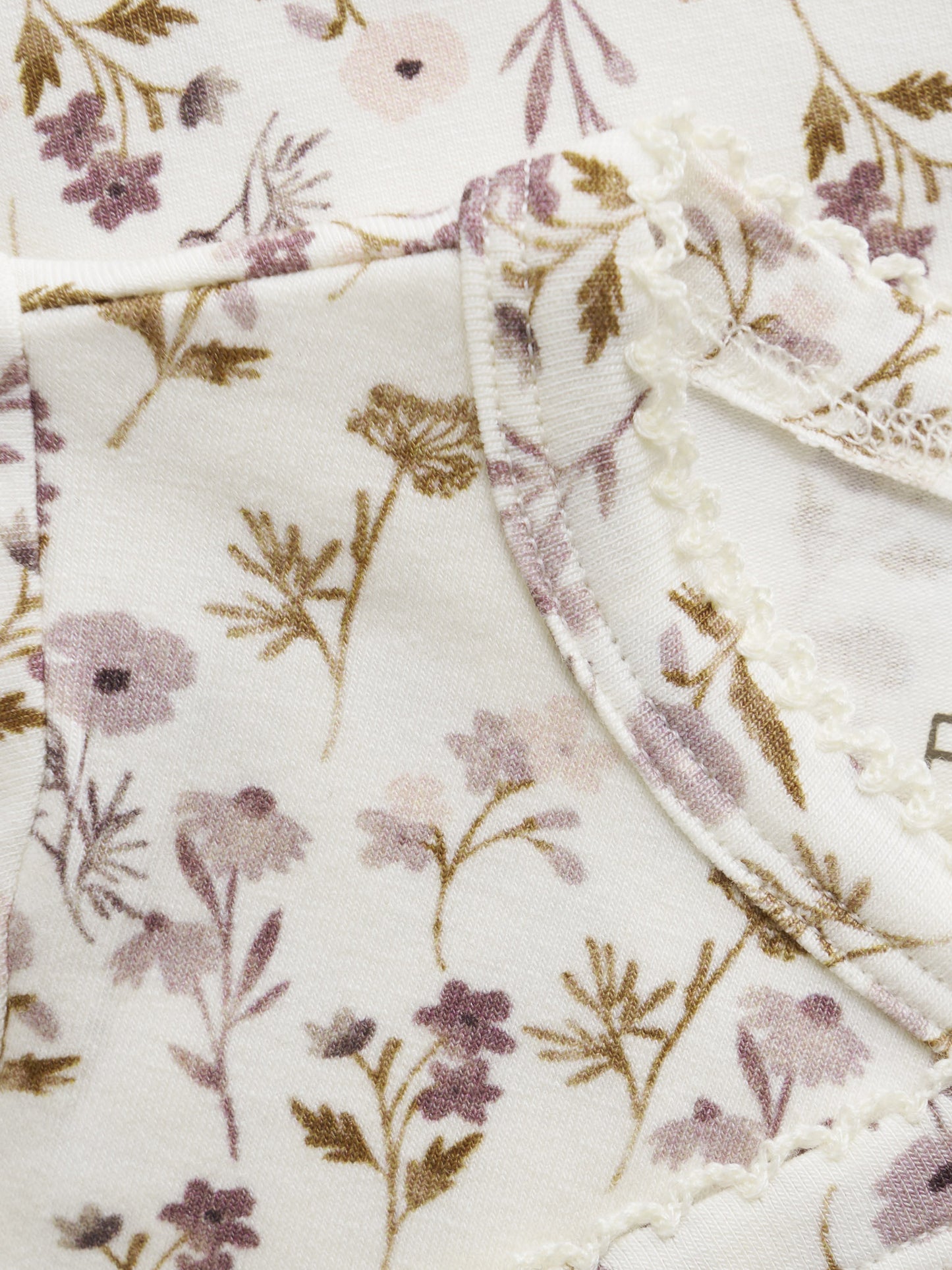 Nahaufnahme des zarten Blumenprints von Fixoni Wickelbody – erhältlich im Bärechind in Winterthur, Zürich, Schweiz
