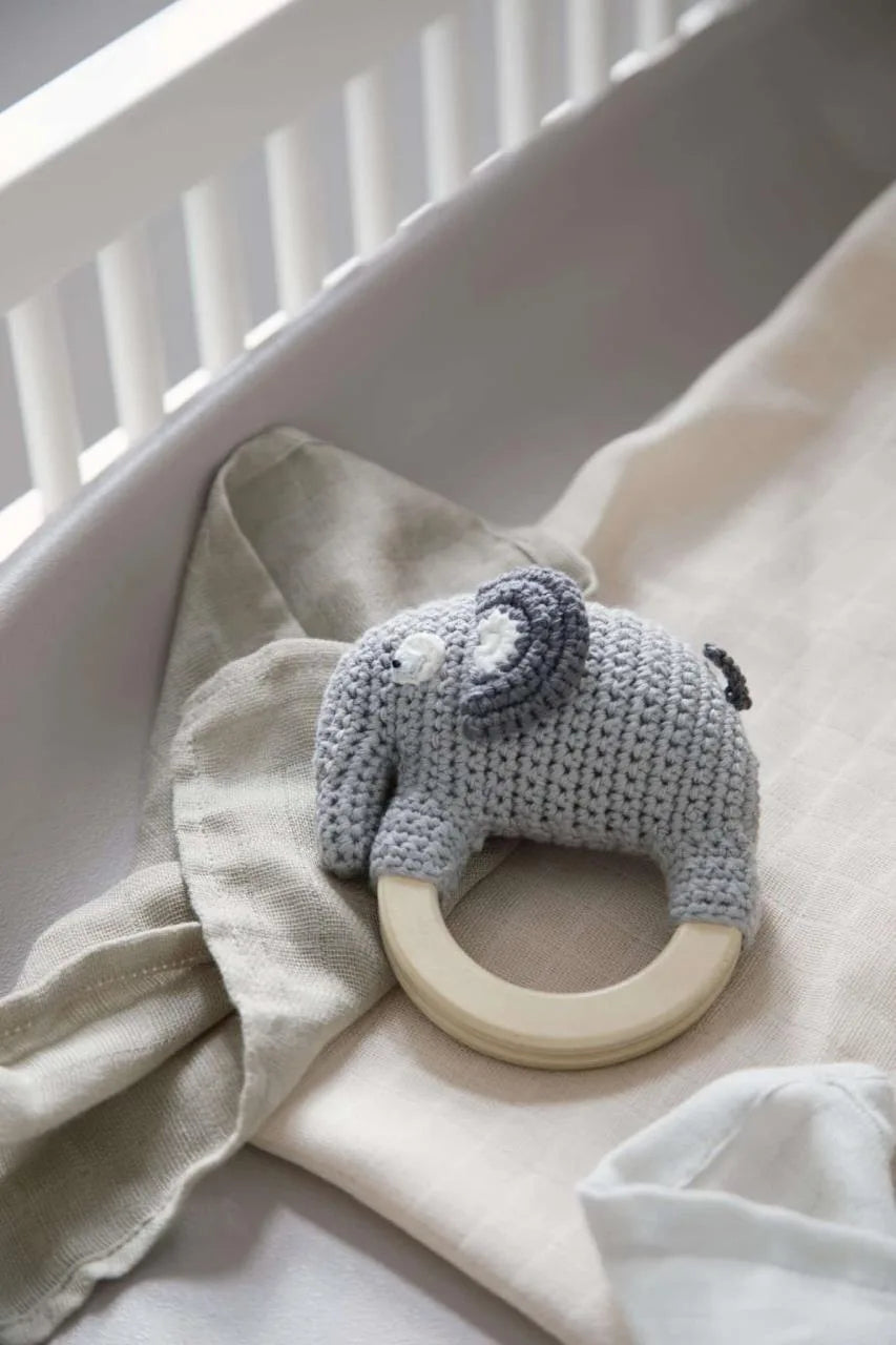 Häkel-Rassel Fanto der Elefant in Grau von Sebra, aus Bio-Baumwolle, dekorativ in einer Babywiege platziert.