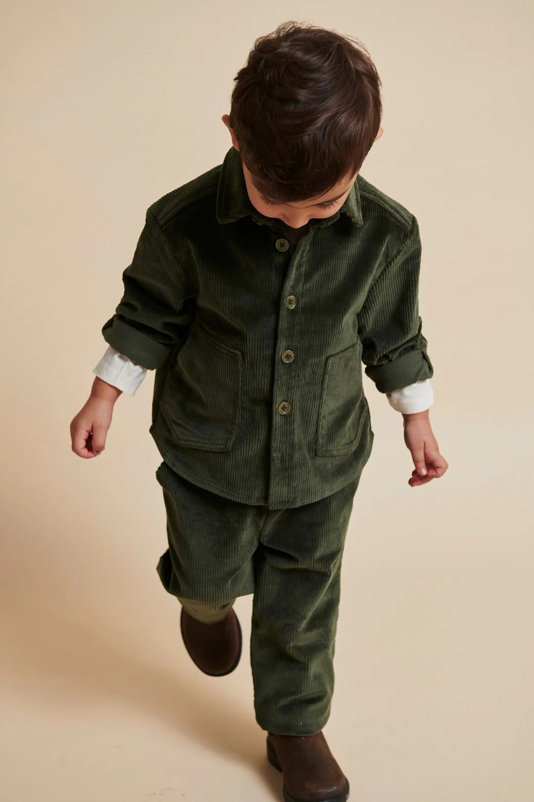 Kind läuft in dunkelgrüner Cordhose aus Baumwolle, fotografiert im Studio, Bärechind Winterthur Zürich Schweiz