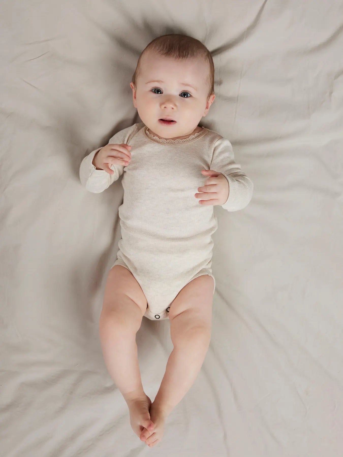 Baby trägt den Langarm Body von name it in Peyote Melange – bequem und süss