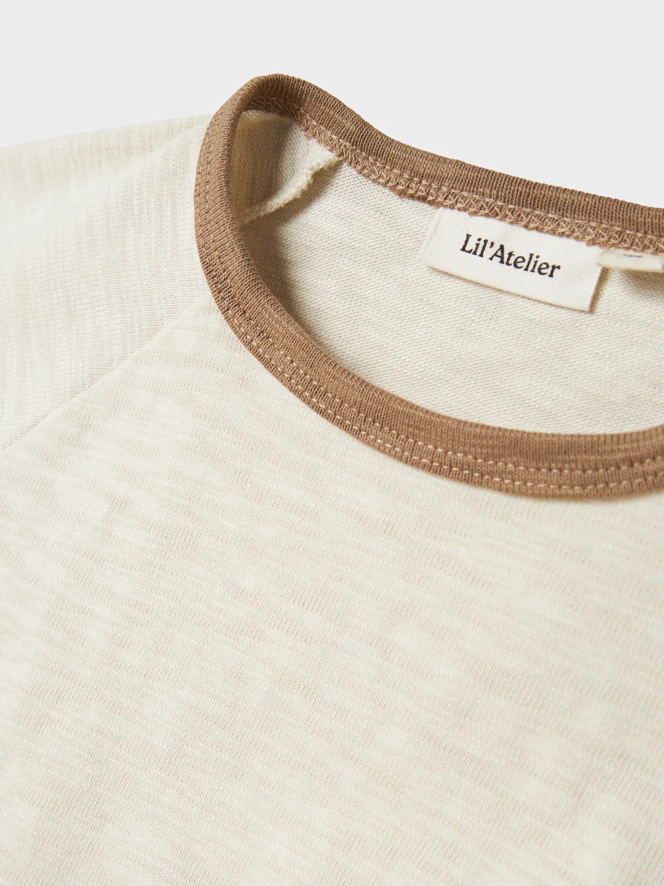 Detailaufnahme vom beigen Lil'Atelier Baumwollshirt mit braunem Kragen, erhältlich bei Bärechind in Winterthur, Zürich Schweiz.
