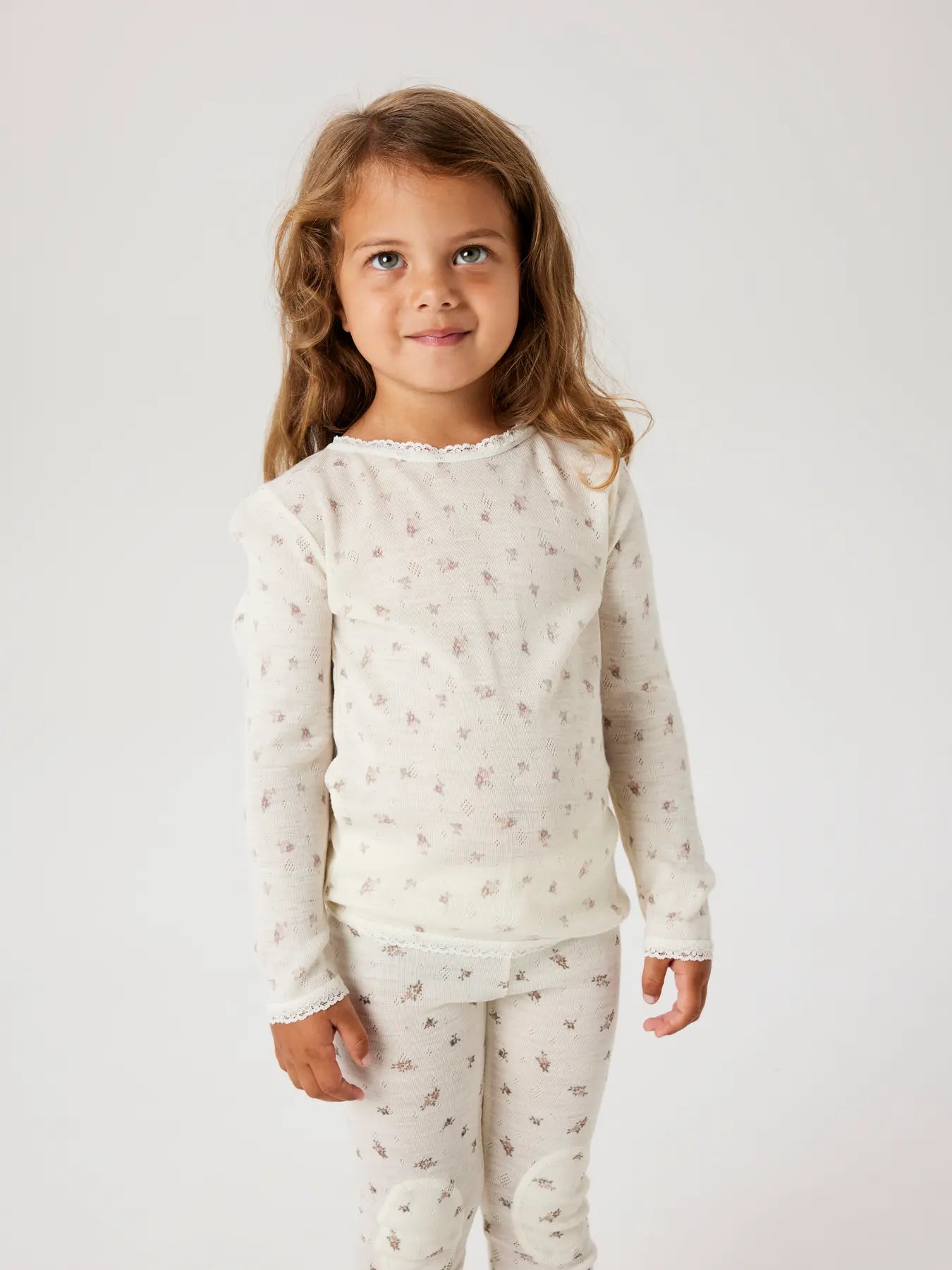 Kind trägt cremefarbenes Langarmshirt aus Wolle mit Blumenmuster – zu kaufen bei Bärechind in Winterthur, Zürich, Schweiz.