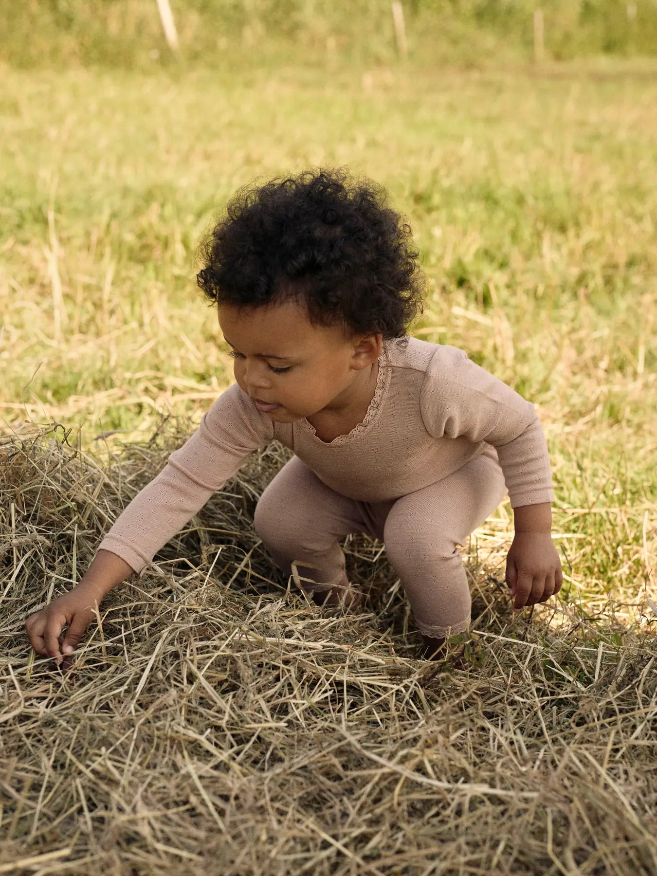 Ein Baby trägt eine weiche Lil’Atelier Merino-Leggings mit Lochmuster und Spitzenabschluss in Winterthur.