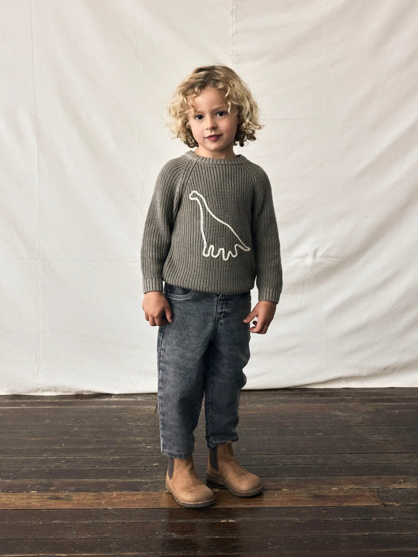 Kind trägt Lil'Atelier Pullover mit Dinosaurier-Motiv aus Bio-Baumwolle bei Bärechind in Winterthur, Zürich, Schweiz.