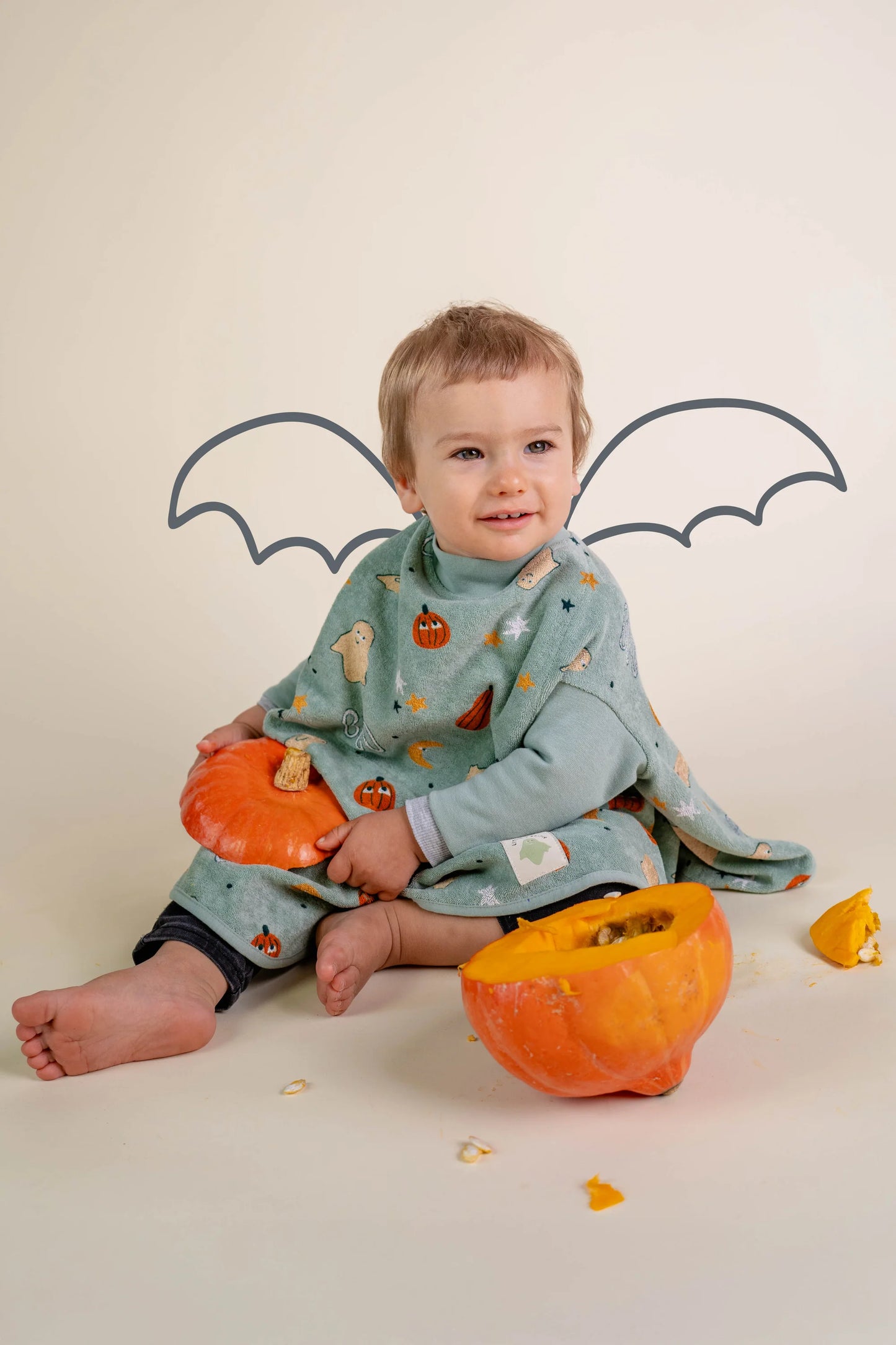 Baby trägt grünes Little Casimir Boo Lätzchen "Halloween" mit Geister- und Kürbis-Muster, erhältlich im Bärechind Winterthur Zürich Schweiz.