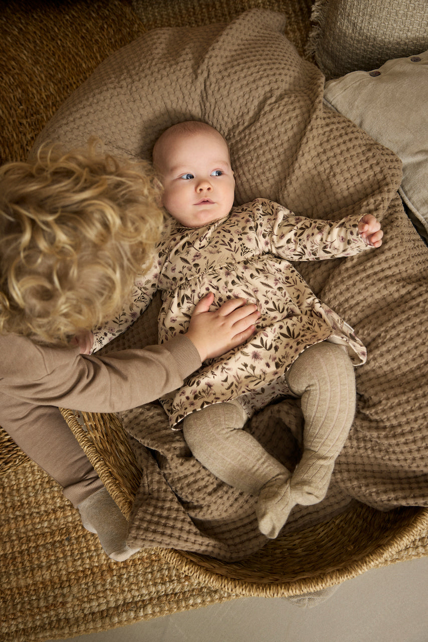 Baby trägt MINYMO Bodykleid mit Blumenmuster – erhältlich bei Bärechind in Winterthur, Zürich, Schweiz.