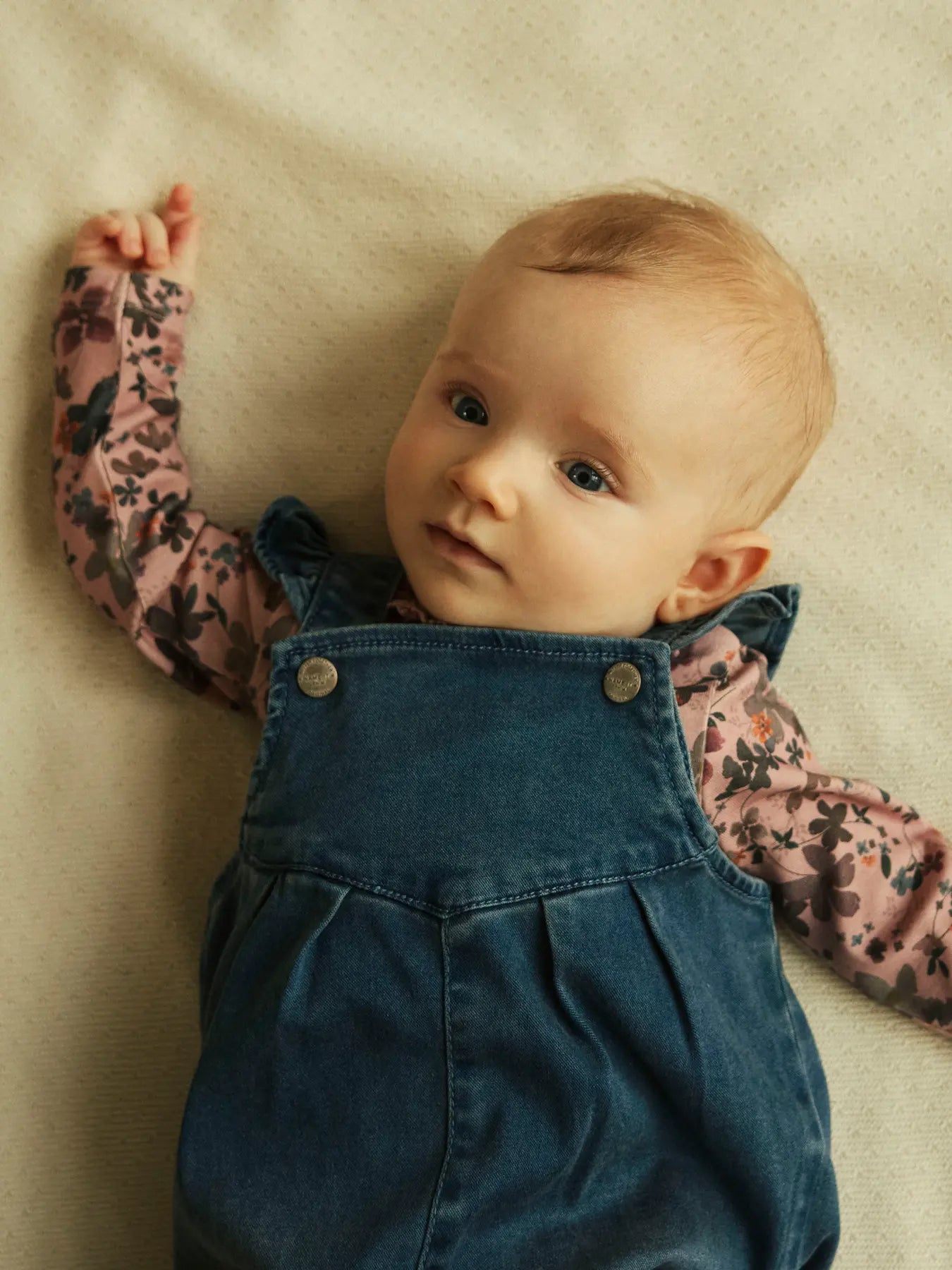 Baby trägt rosa NAME IT Body mit Blumenmuster aus Bio-Baumwolle – erhältlich bei Bärechind in Winterthur, Zürich, Schweiz.
