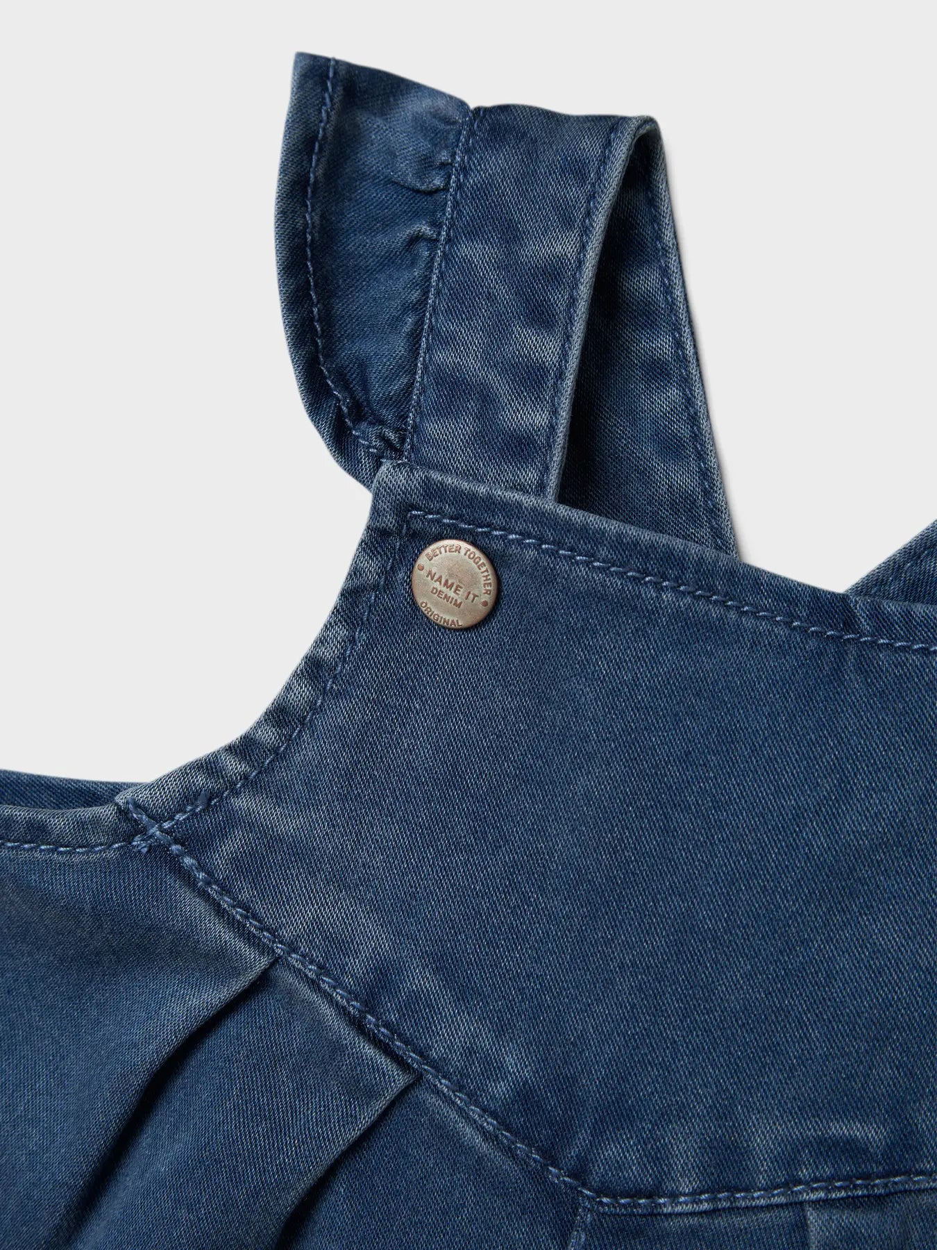 Rüschen-Träger und Druckknopf der NAME IT Latzhose aus TENCEL™ – zu kaufen bei Bärechind in Winterthur, Zürich, Schweiz.