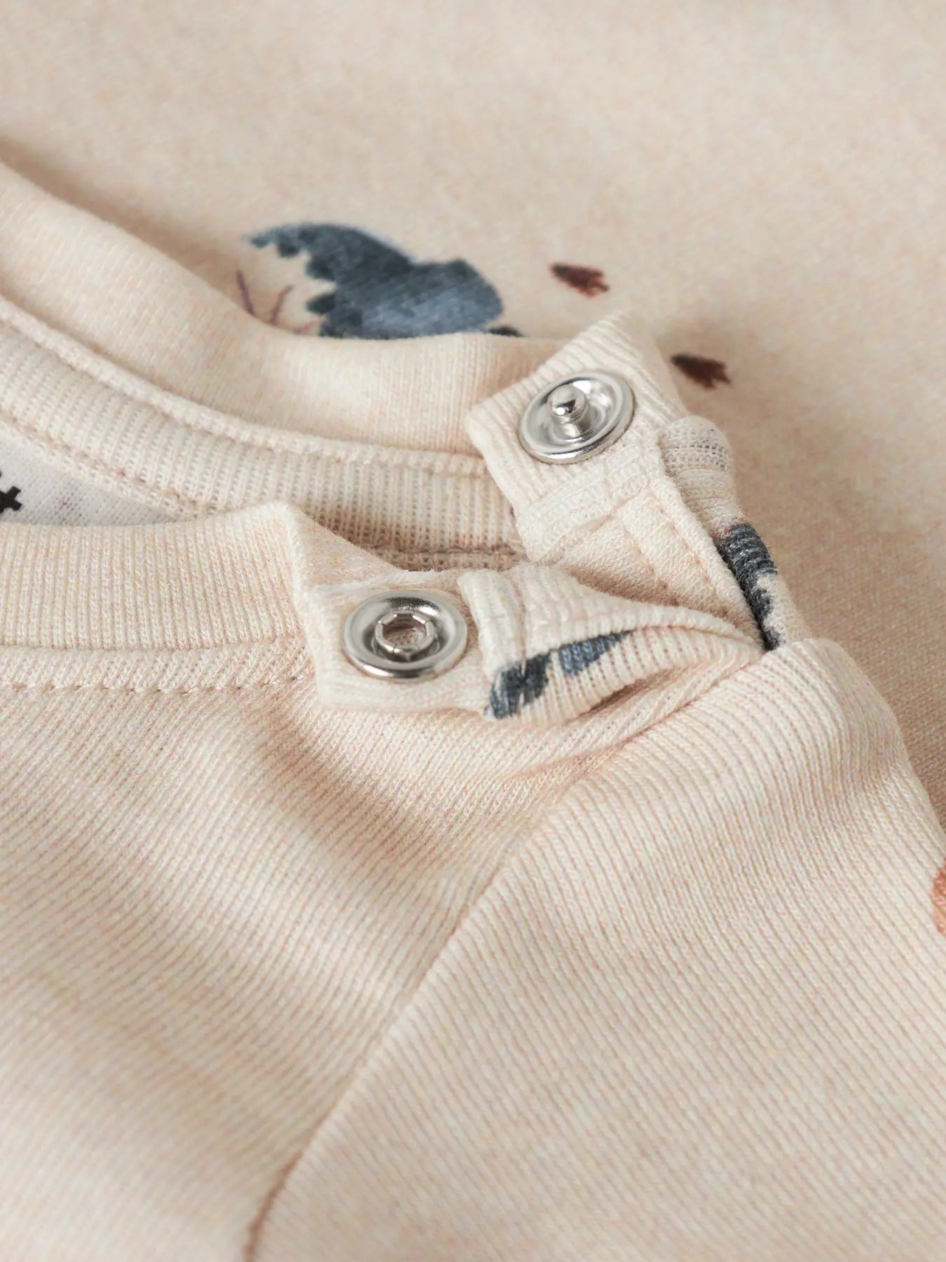 Detailaufnahme der Druckknöpfe und des Dino Musters auf einem NAME IT Babybody bei Bärechind Winterthur Zürich Schweiz