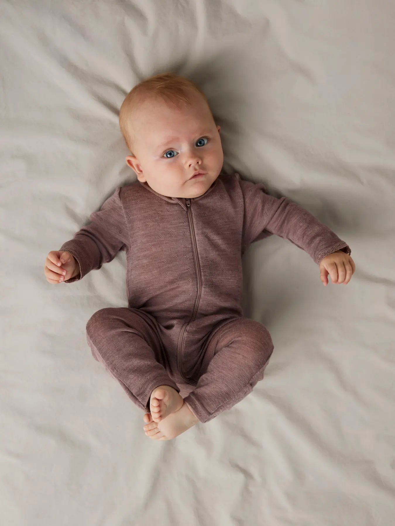Baby im Name it Merino-Schlafanzug in Rosenholz mit Reissverschluss und umklappbaren Füssen – erhältlich in Winterthur.
