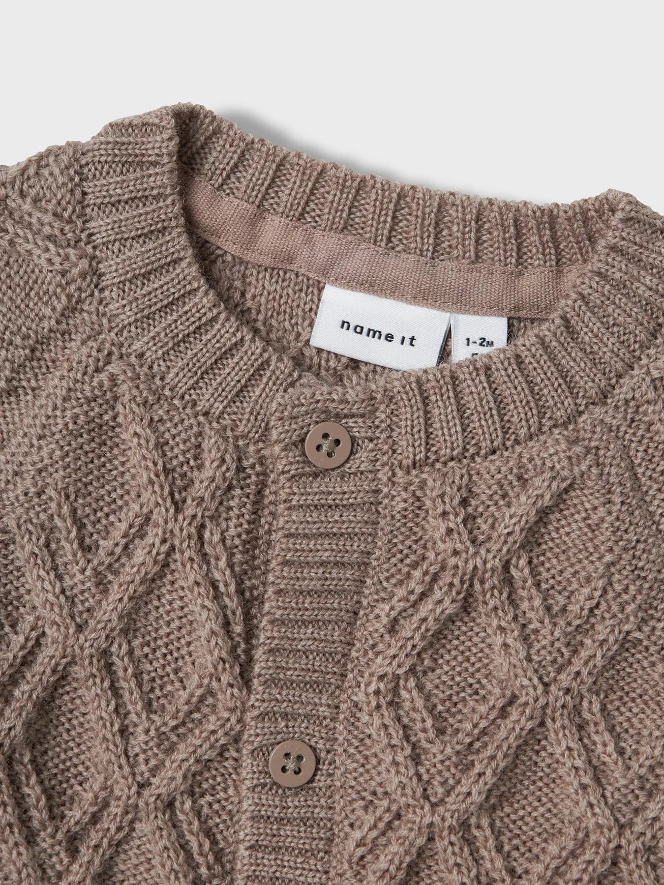 Nahaufnahme der Strickstruktur und Knopfleiste der Merinojacke von Name It in Winterthur.