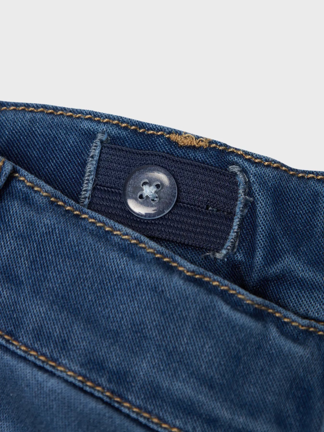 Detailaufnahme vom Bund und Knopf der Nmfsalli Kinderjeans – elastisch & verstellbar