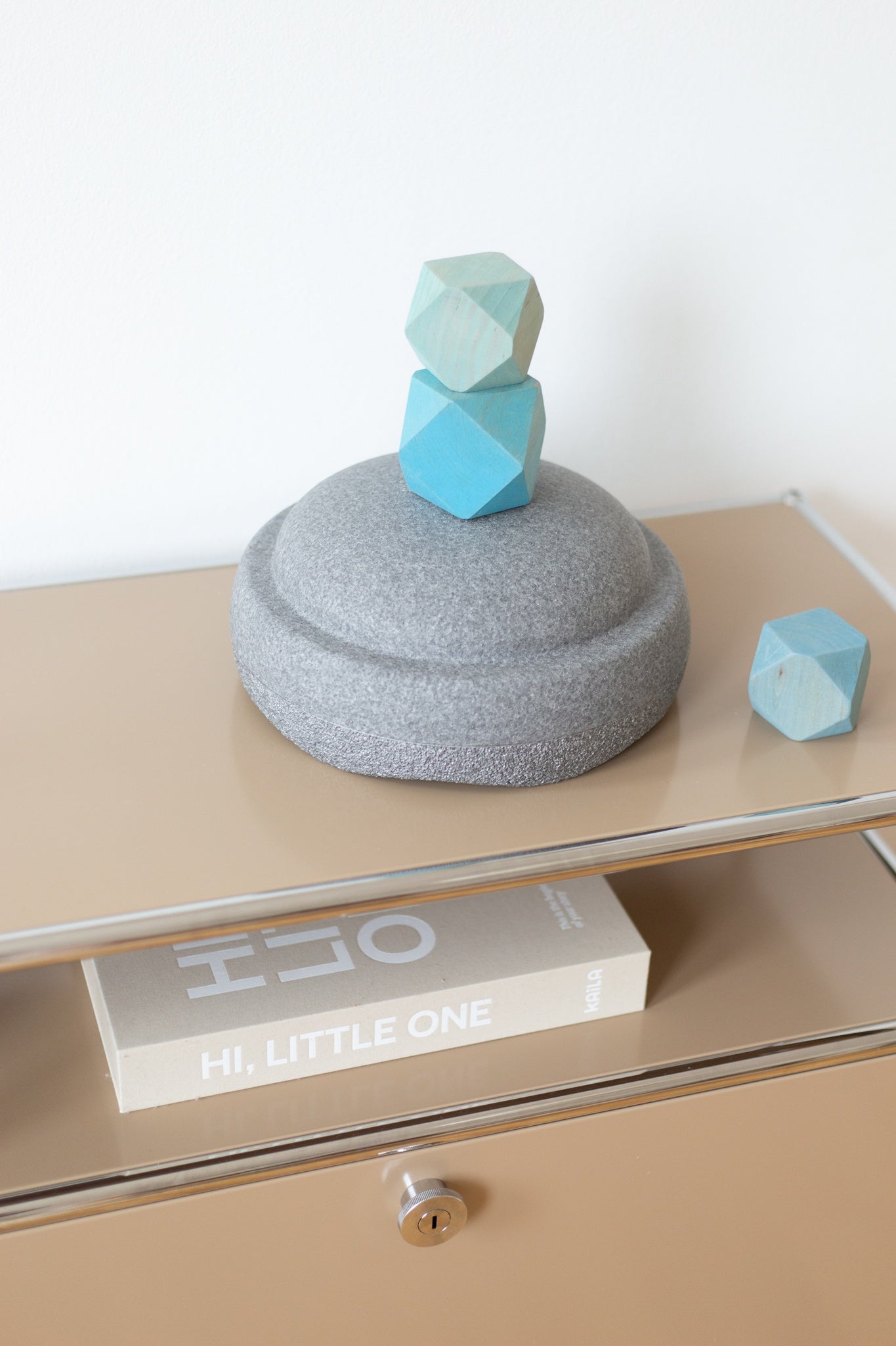 Grauer Stapelstein mit Spielfigur auf Holzkommode – dezentes Design aus nachhaltigem Material für Chind in der Schweiz