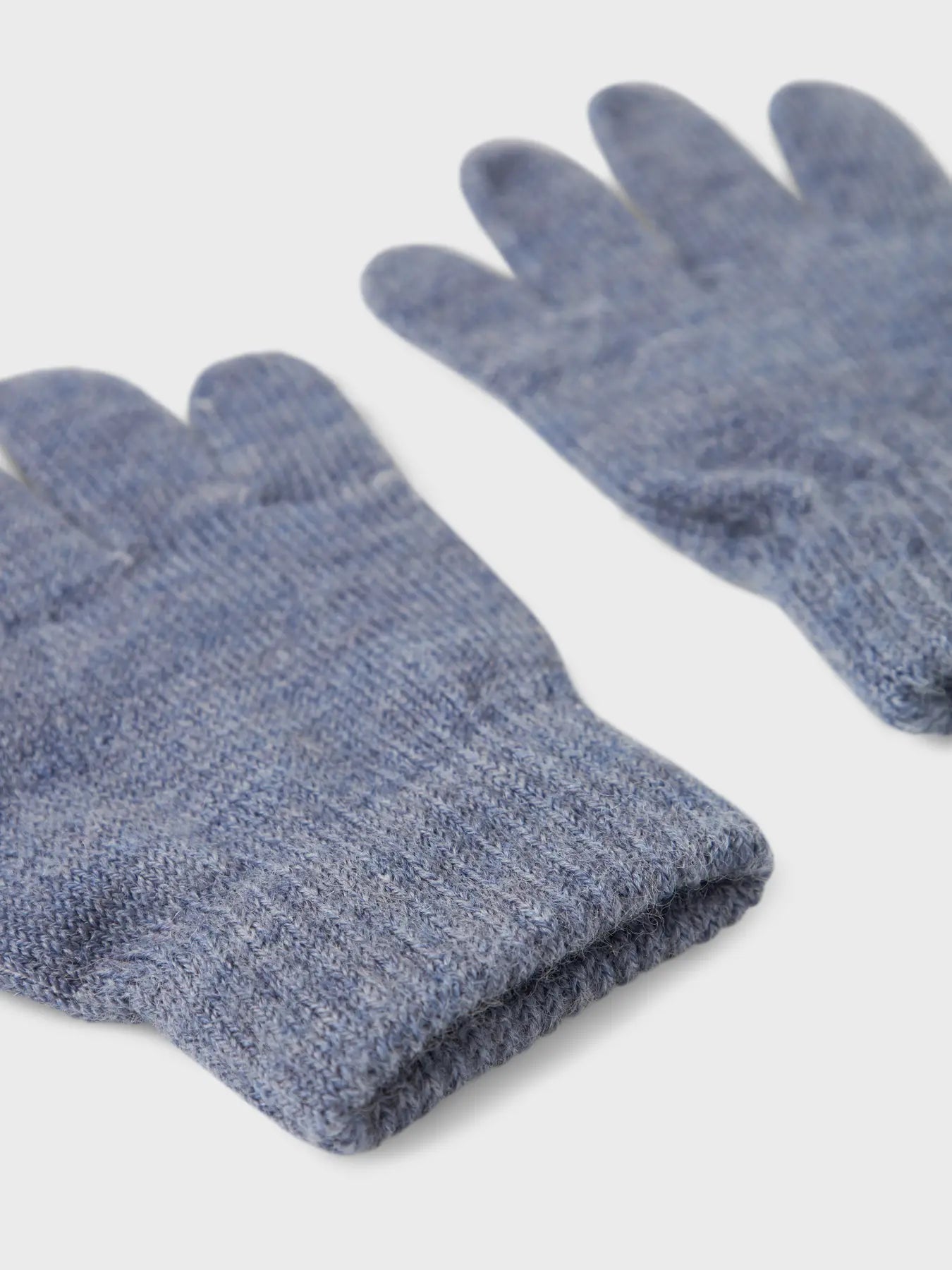 Detailansicht eines blauen Strickhandschuhs aus Wolle mit Bündchen.