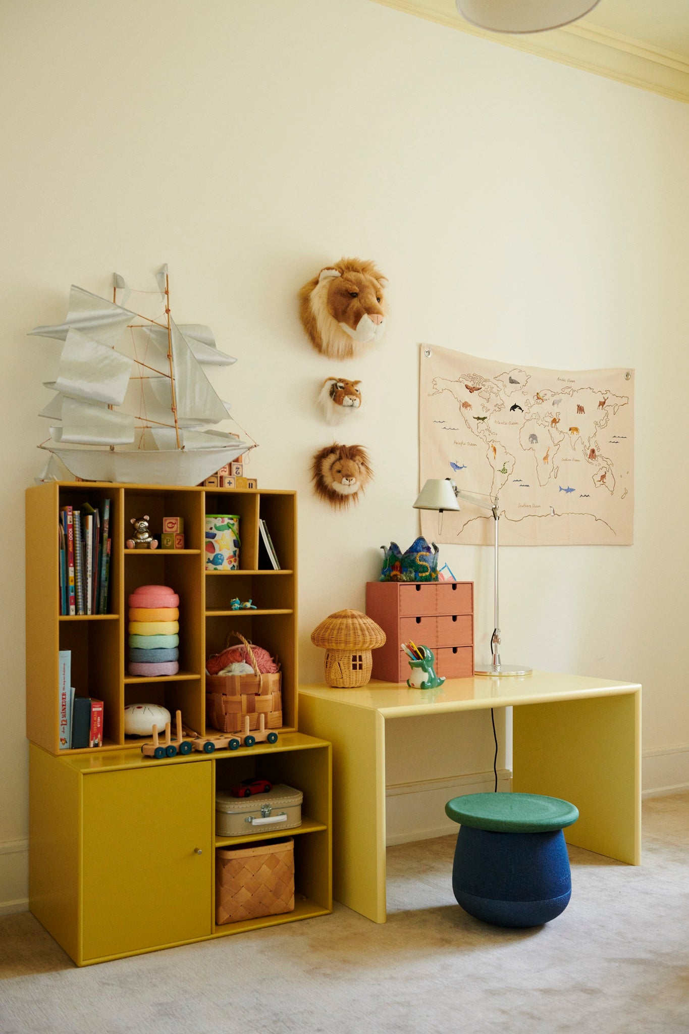 Schaumstoff-Hocker in Dunkelblau mit grünem Deckel in einem gemütlichen Kinderzimmer neben Regalen und Spielsachen.