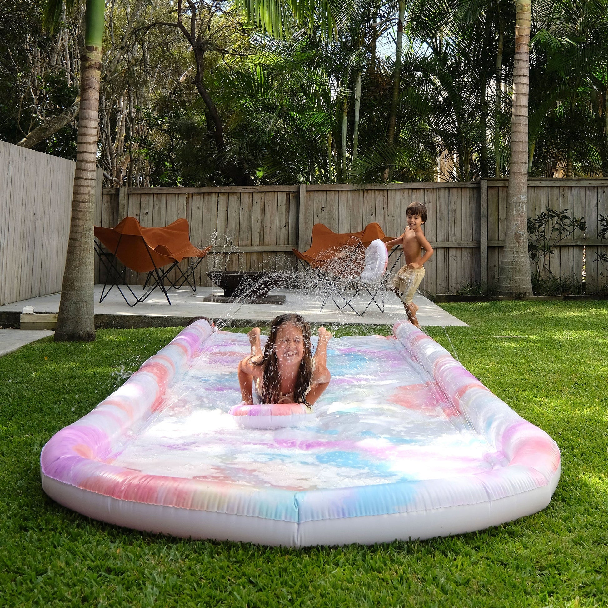 Zwei Kinder spielen gemeinsam auf der Sunnylife Slip n Slide Wasserrutsche im Garten - Bärechind Winterthur