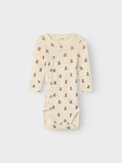 Baby trägt den Wickelbody von Lil' Atelier mit süssem Teddymuster – ideal für sensible Haut.