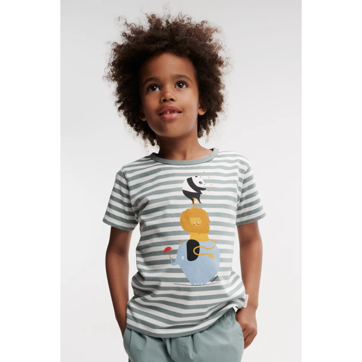 Kind trägt Apia Kurzarm-T-Shirt mit verspieltem Print – Bequemes, hautfreundliches Kinder-T-Shirt aus Bio-Baumwolle. Perfekt für den Alltag. Erhältlich in Winterthur, Zürich, Schweiz.