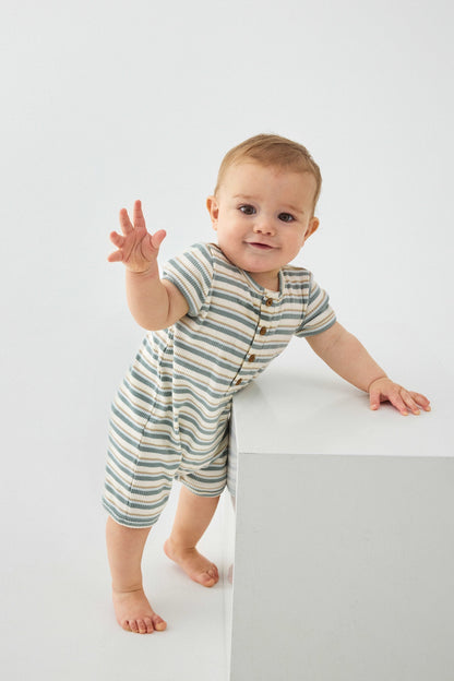 Baby trägt Grün gestreifter MINYMO Rib Strampler aus Bio-Baumwolle, erhältlich im Bärechind in Winterthur, Zürich, Schweiz