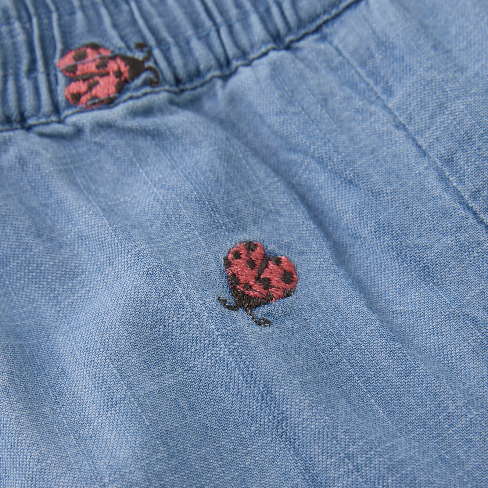 Nahaufnahme der Baby-Jeans mit feiner Marienkäfer-Stickerei und weichem Denim-Stoff