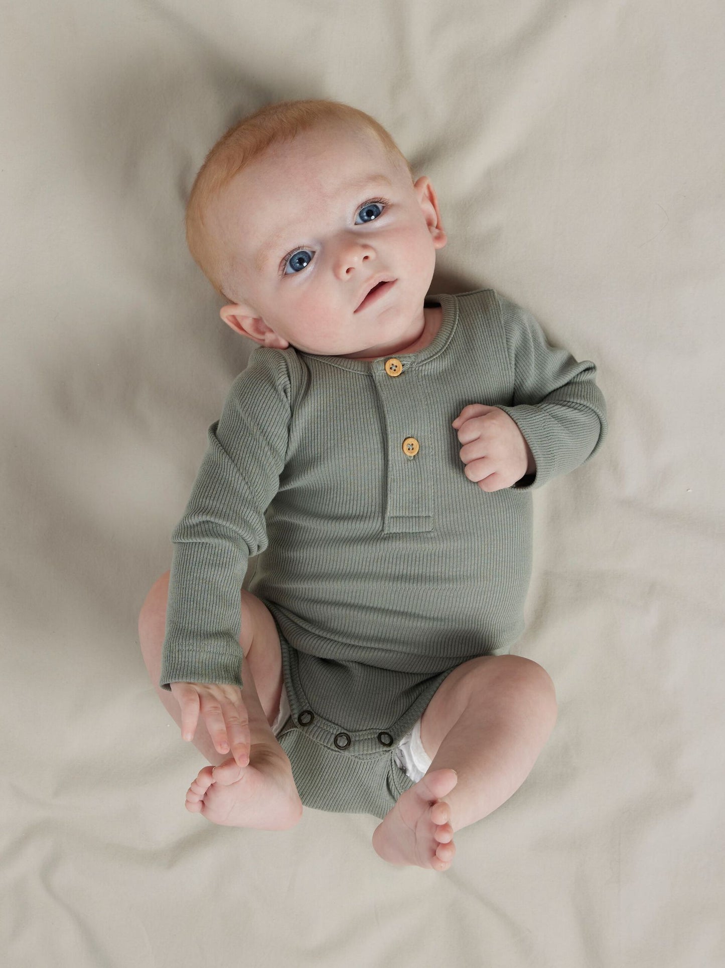 Alt-Text: Baby trägt grauen Langarmbody aus Bio-Baumwolle, weich und bequem. Erhältlich bei Bärechind in Winterthur, Zürich Schweiz.