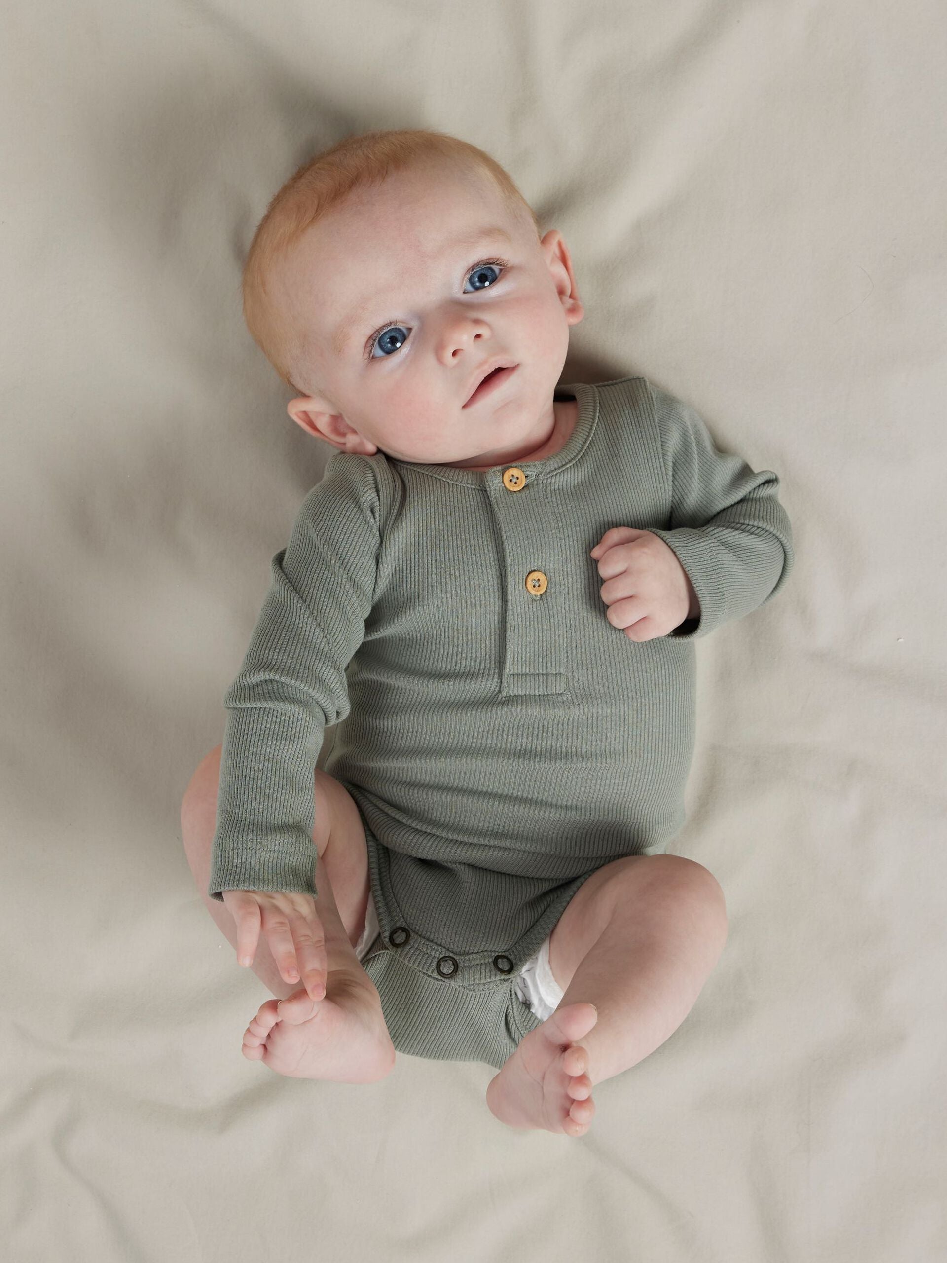 Alt-Text: Baby trägt grauen Langarmbody aus Bio-Baumwolle, weich und bequem. Erhältlich bei Bärechind in Winterthur, Zürich Schweiz.