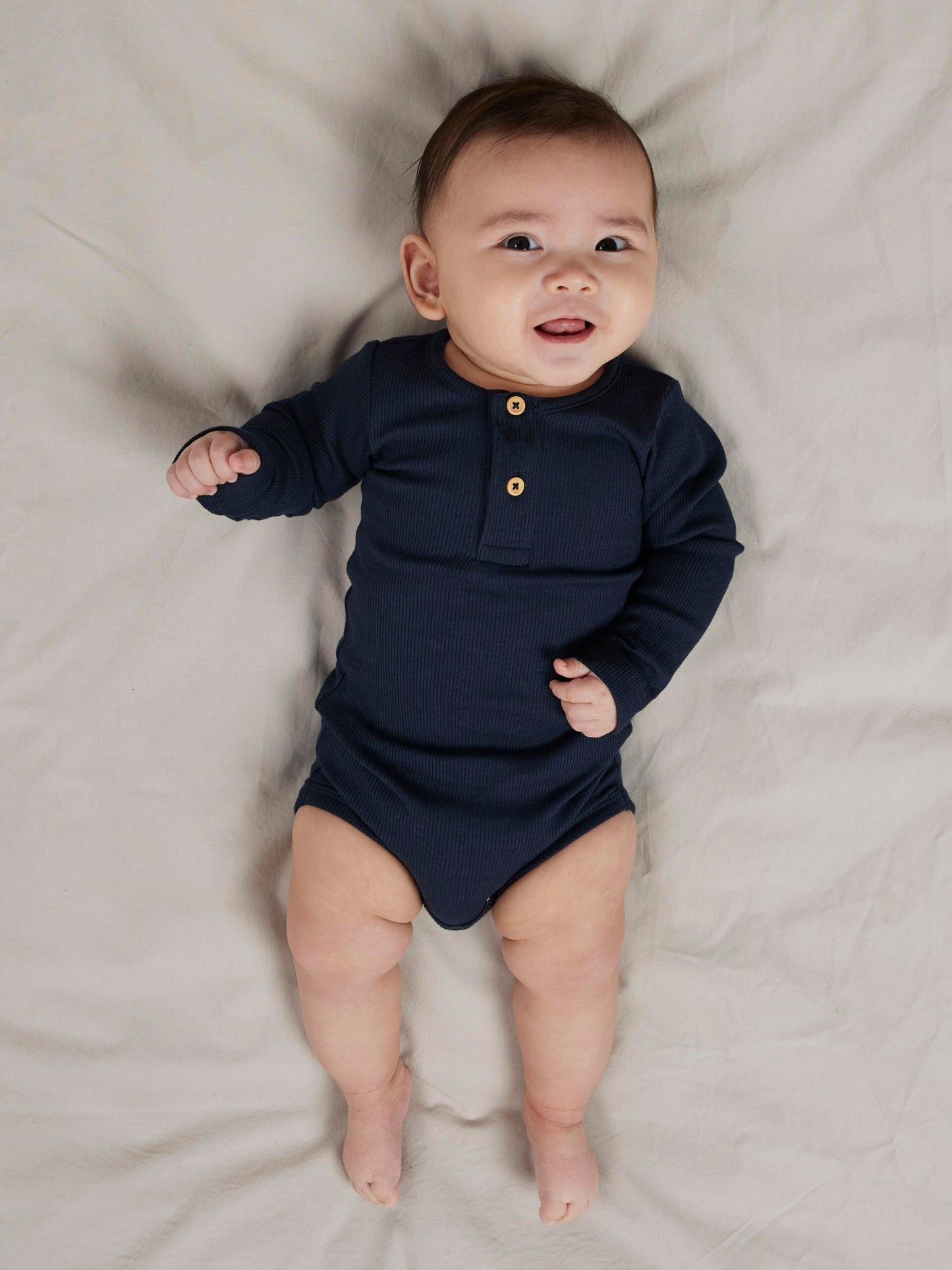 Alt-Text: Baby trägt weichen Langarmbody in Vintage Indigo Melange. Erhältlich bei Bärechind in Winterthur, Zürich Schweiz