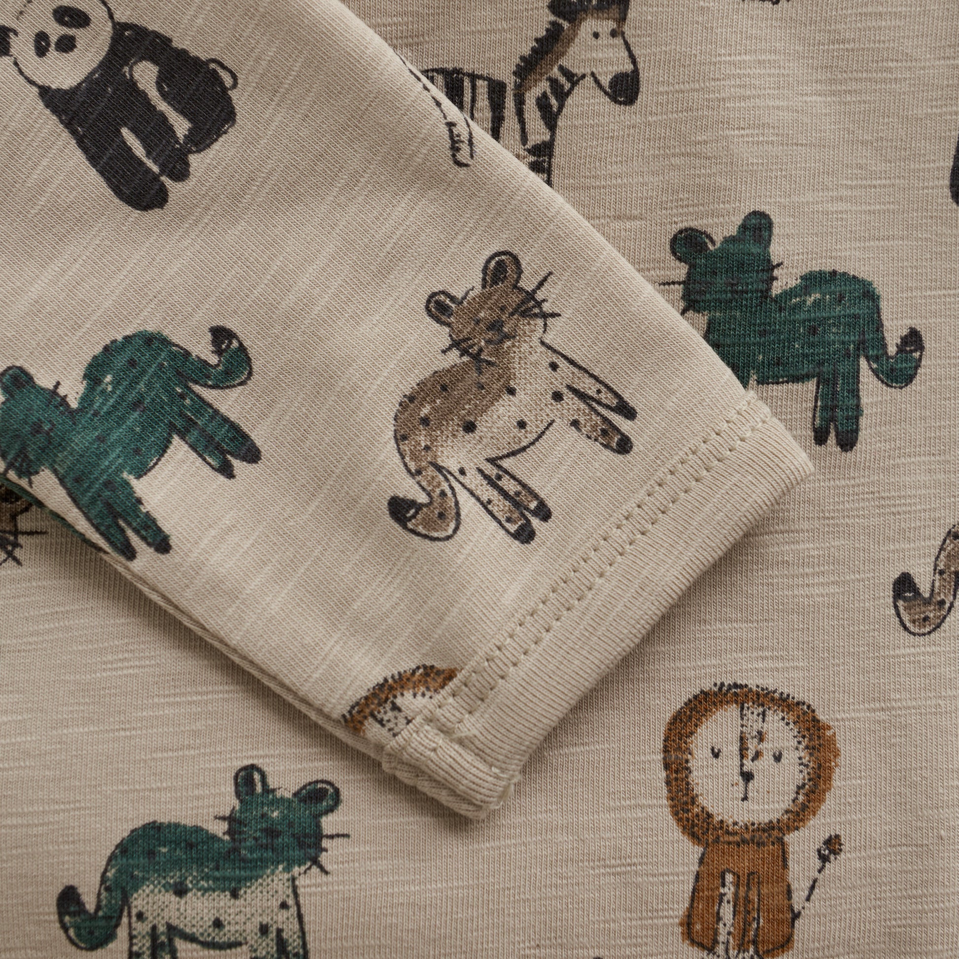 Detailansicht vom Langarm-Babybody aus Baumwolle in Cappuccino mit buntem Tierprint – erhältlich bei Bärechind Winterthur