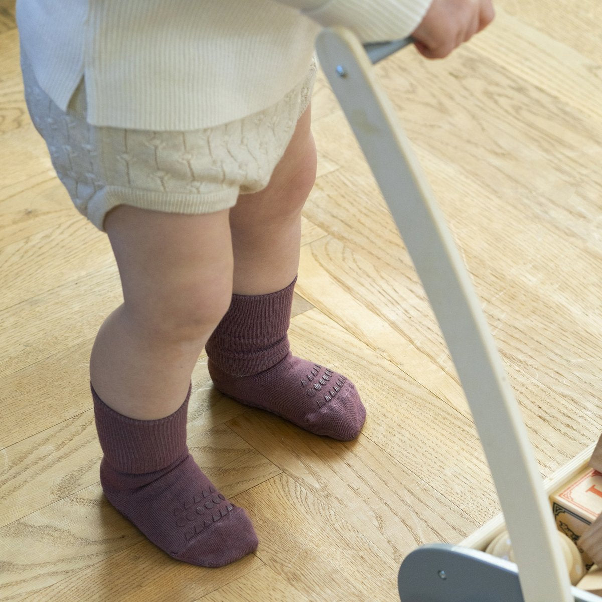 Chind in Bewegung mit mistyplumfarbenen Anti-Rutsch-Socken von GoBabyGo – ideal für erste Schritte, Bärechind, Winterthur