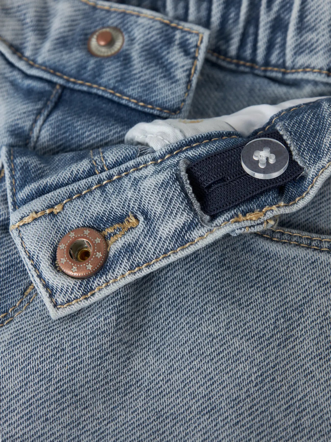 Detailaufnahme von Knopf und Denimstoff der hellblauen Kinder Shorts von NAME IT, Bärechind Winterthur, Zürich, Schweiz.