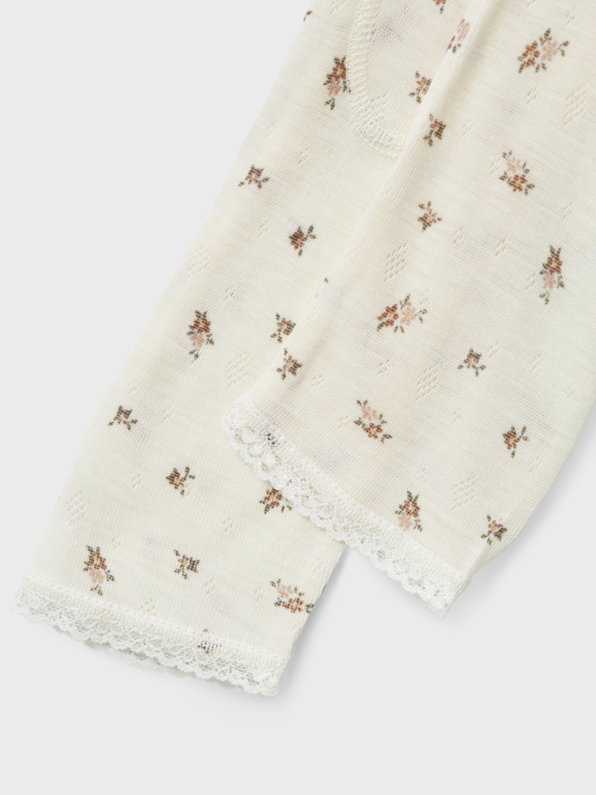 Detailansicht des zarten Blumenprints auf weisser Merinowolle