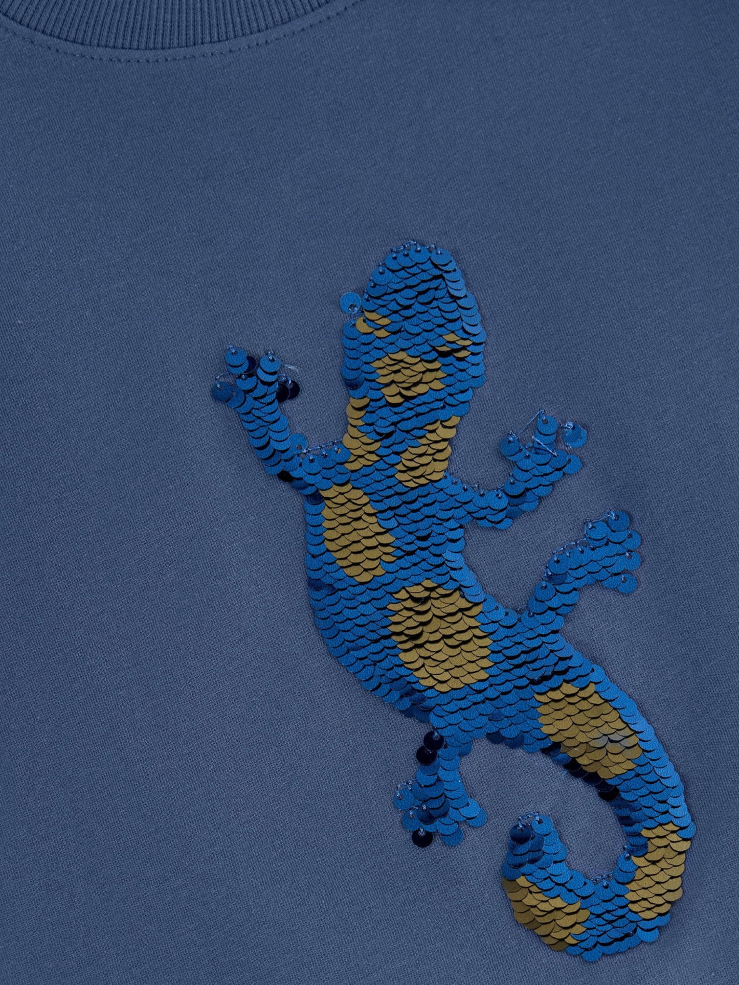 Detailansicht des funkelnden Pailletten-Geckos auf dem Minymo Shirt – Fair Fashion für Kinder im Bärechind in der Schweiz.