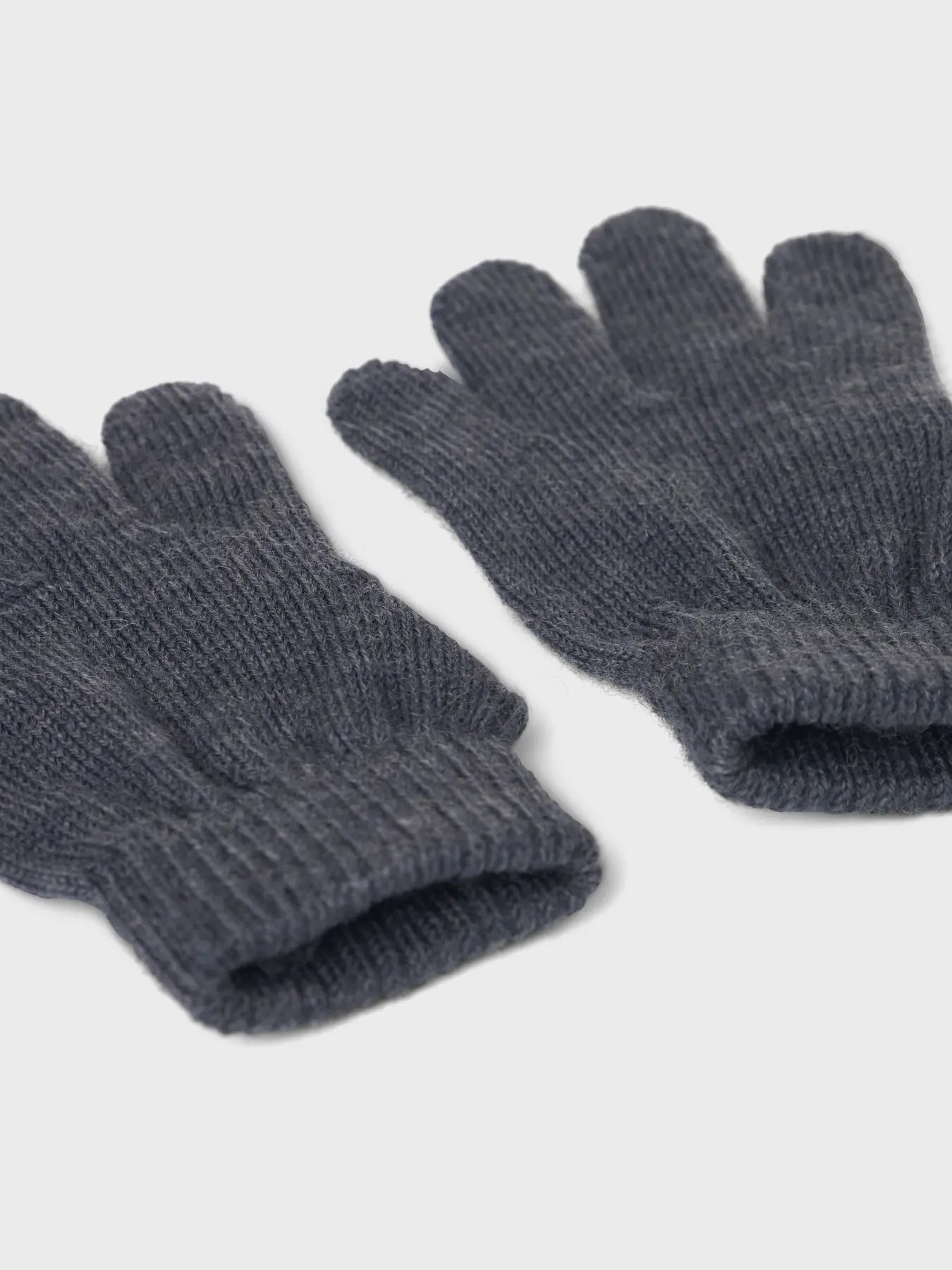 Nahaufnahme von Bündchen und Strickstruktur eines dunkelblauen Wollhandschuhe.

