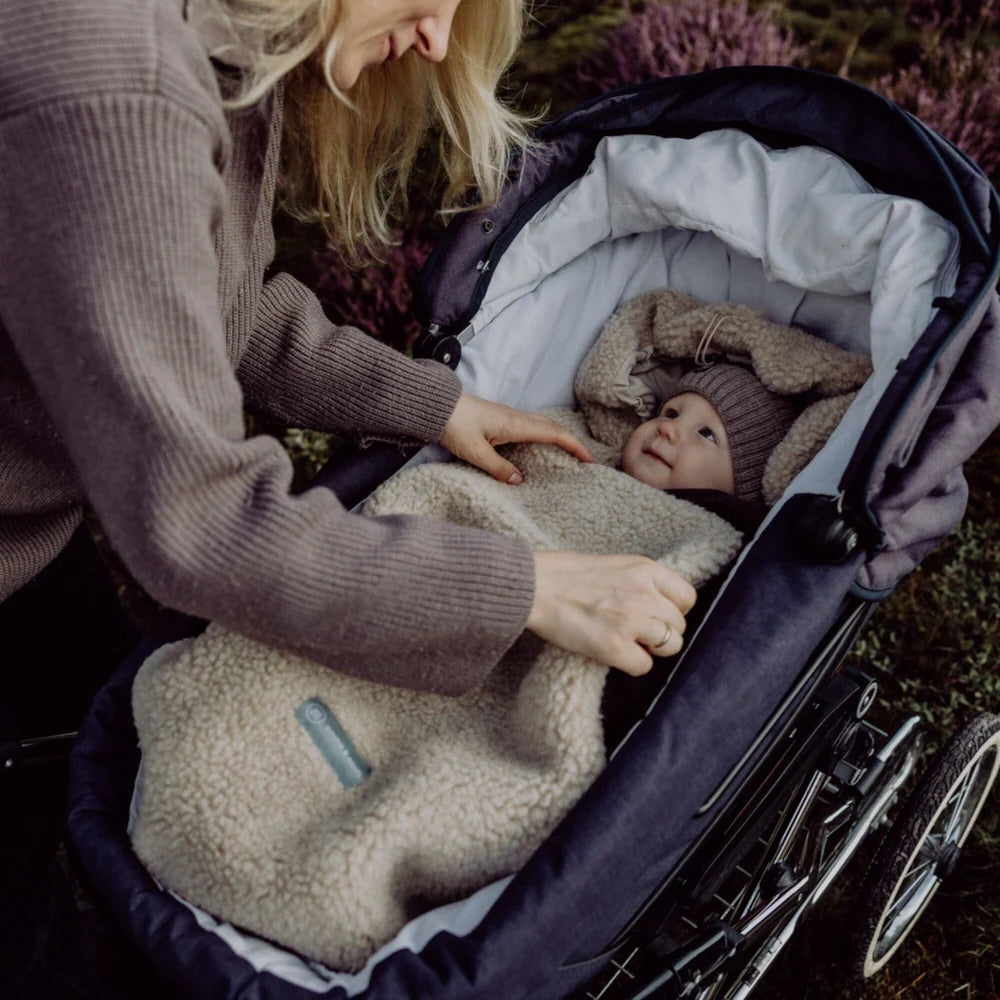 Baby im Emma & Noah Merino Kinderwagenfusssack Braun im Kinderwagen