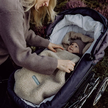 Baby im Emma & Noah Merino Kinderwagenfusssack Braun im Kinderwagen