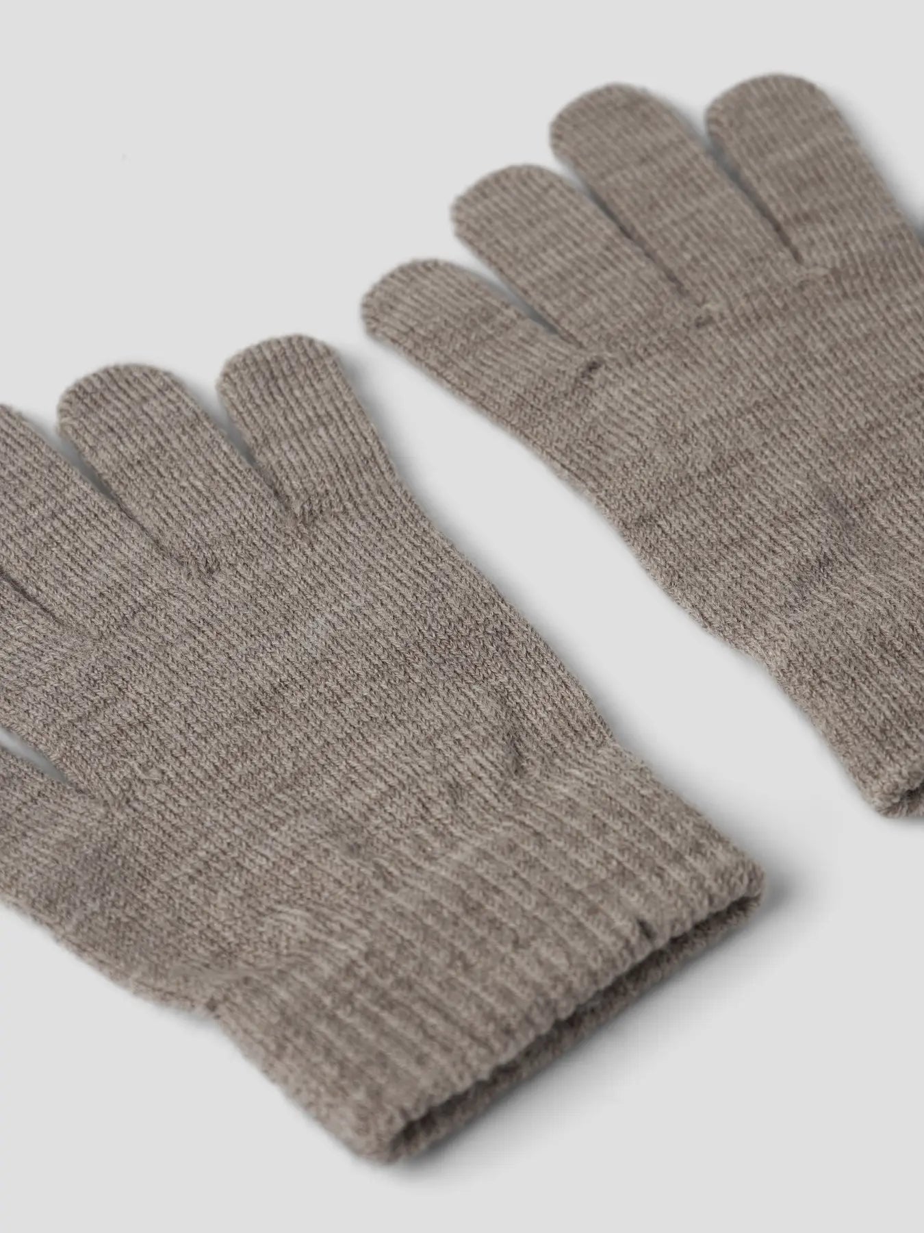 Nahaufnahme eines naturbraunen Strickhandschuhs mit weichem Bündchen.