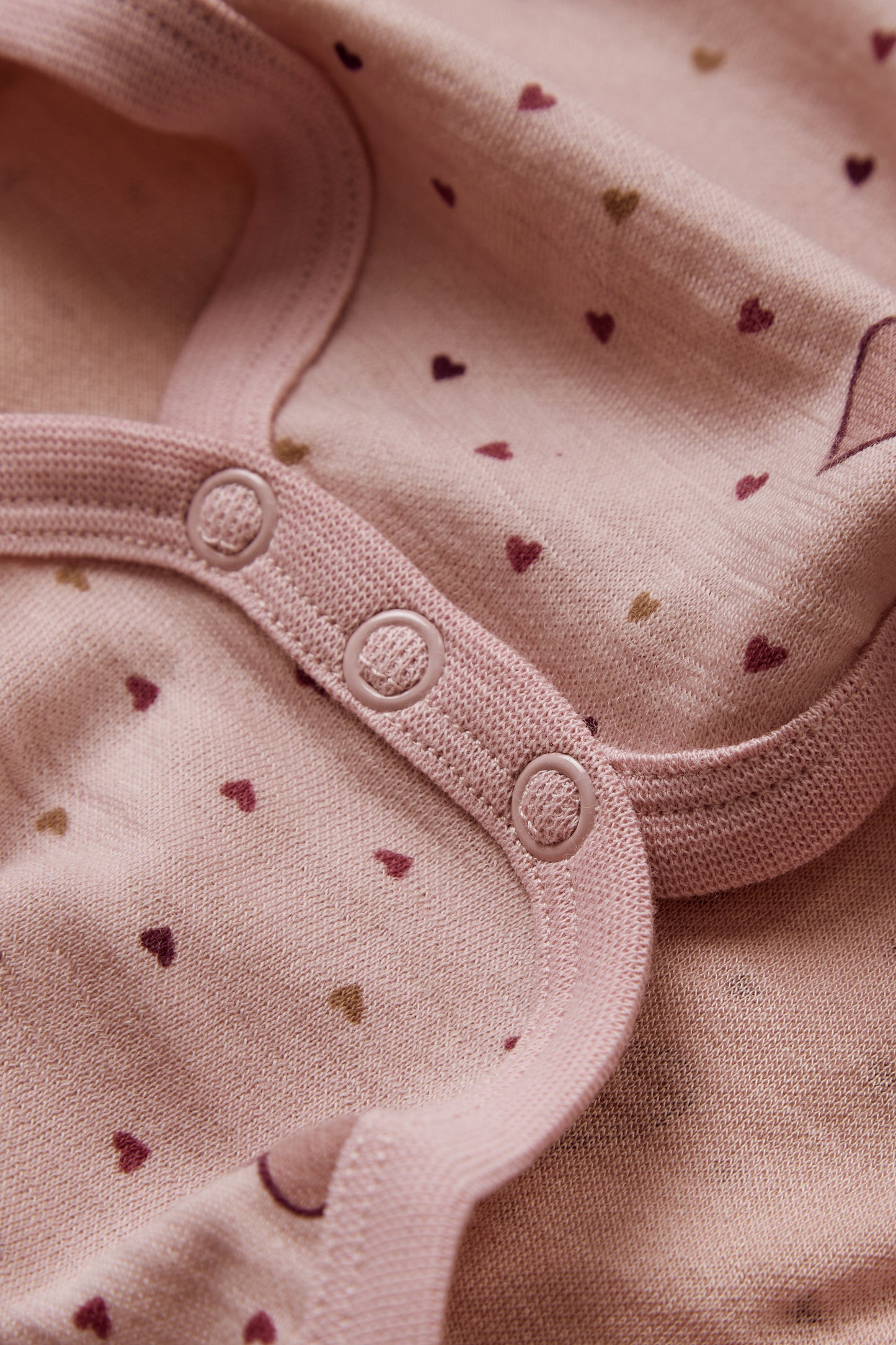 Nahaufnahme der Druckknöpfe und Herzchenprint auf dem Baloo Body in Dusty Rose